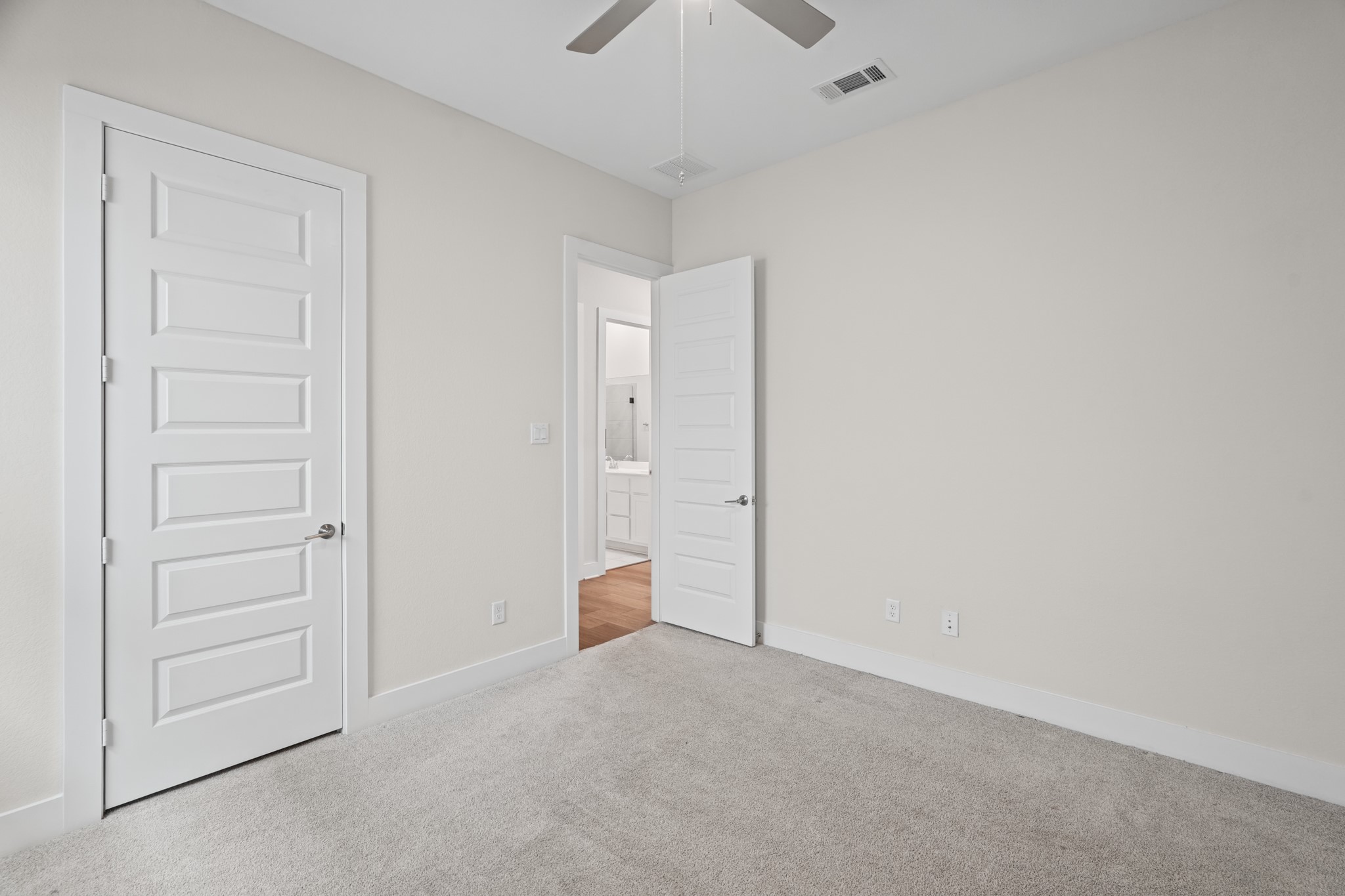 Hallway connecting the secondary bedrooms and bath, with wide doorways, linen storage and the same bright, neutral palette carried consistently throughout the home.
