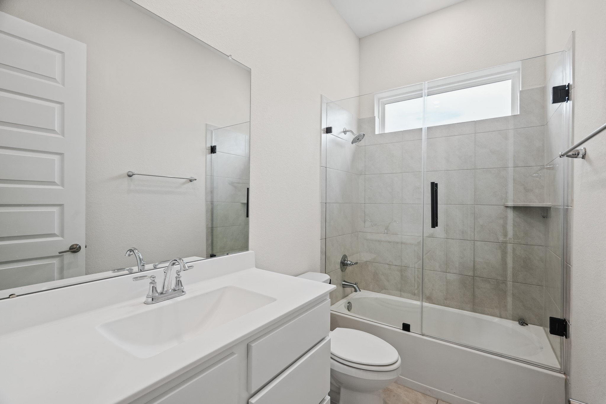 Full bath with a single vanity, a framed mirror and a glass-enclosed shower finished in clean, light tile - bright, low-maintenance and practical for everyday use.