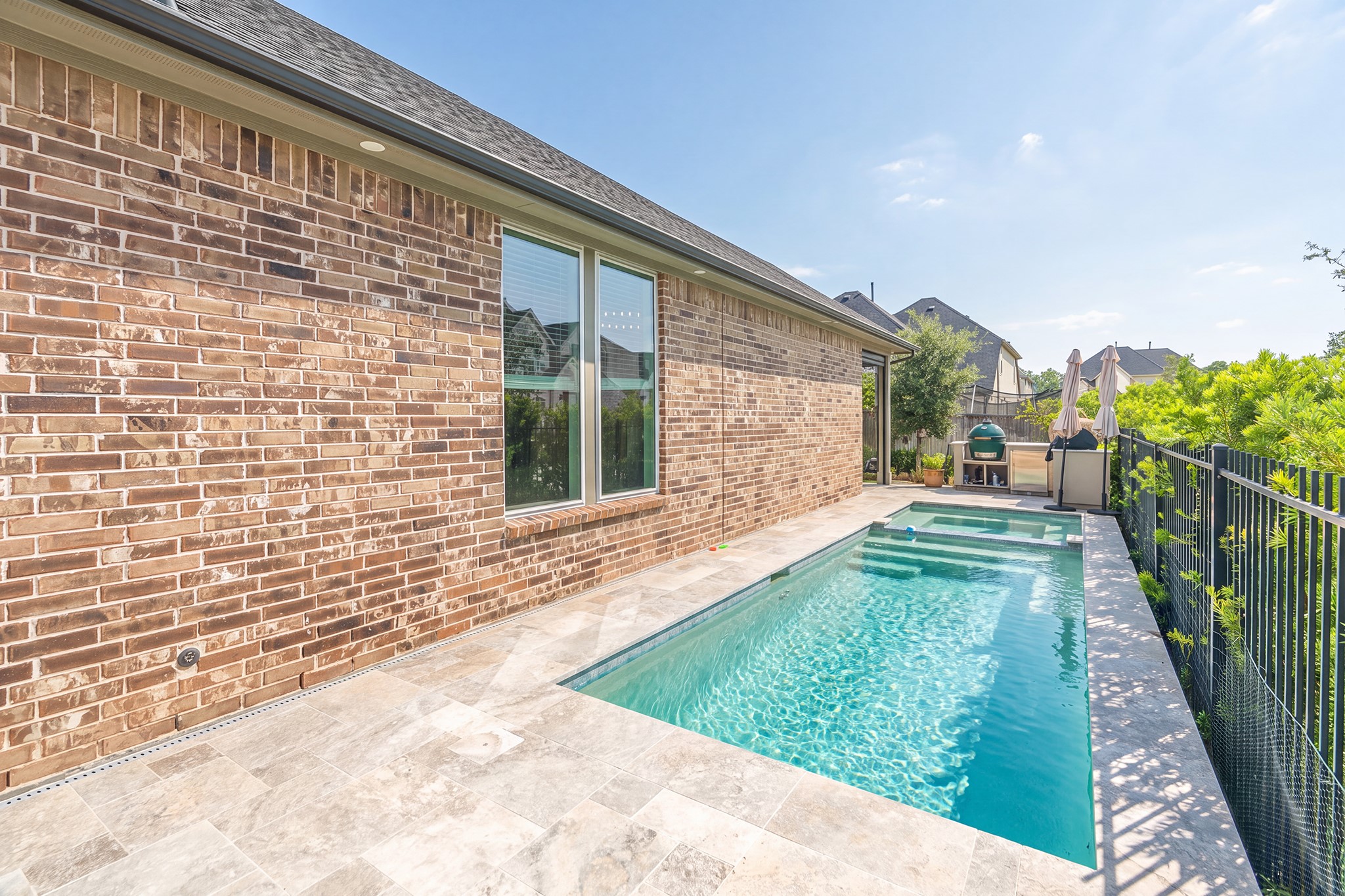 The pool runs alongside the home, bordered by wide decking and brick - a private retreat for cooling off and relaxing through the long Houston-area summers.