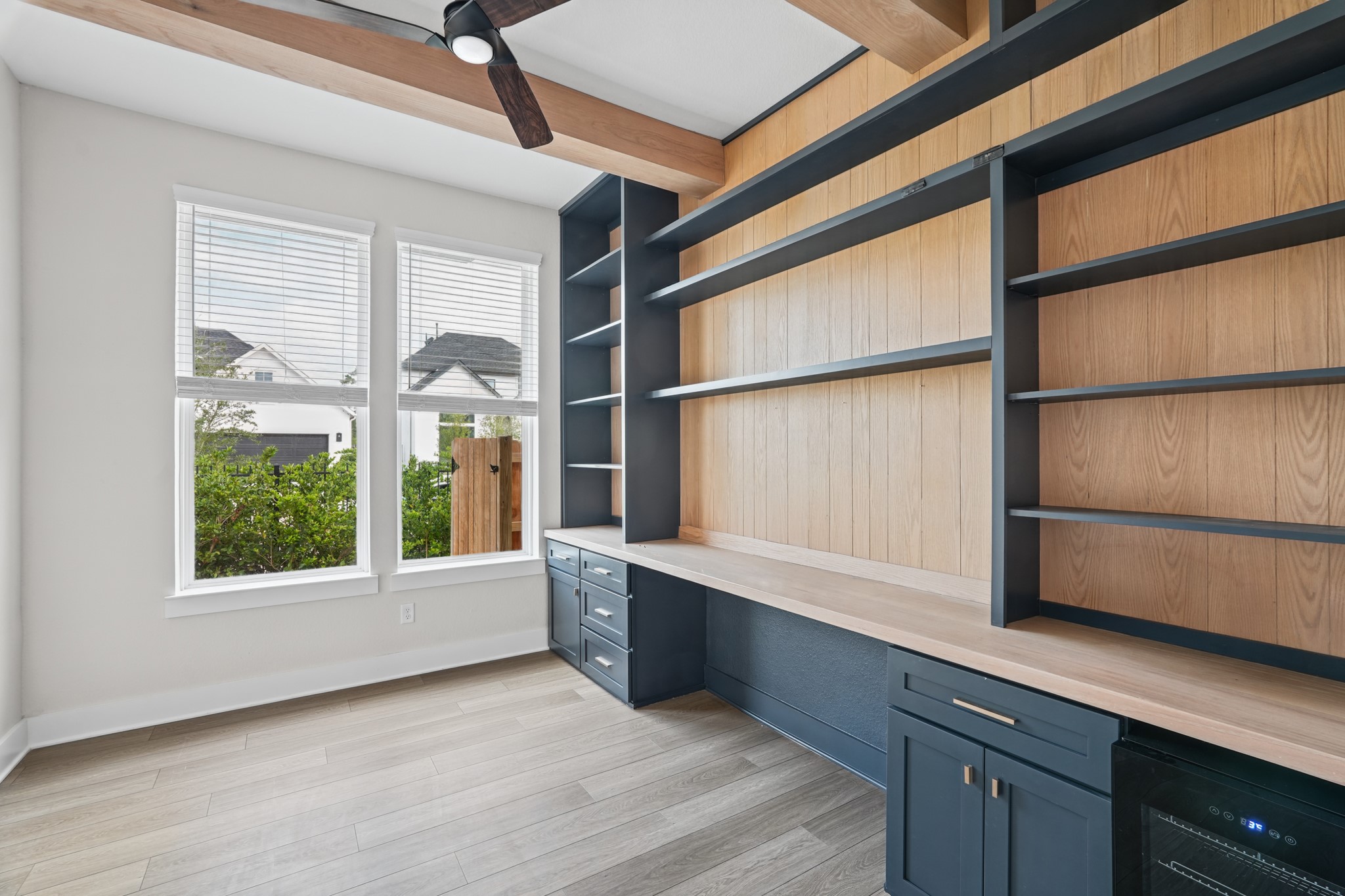 Built-in desk and open shelving line the study wall, with a window bringing in natural light and generous cabinet storage below for files, books and everyday office essentials.