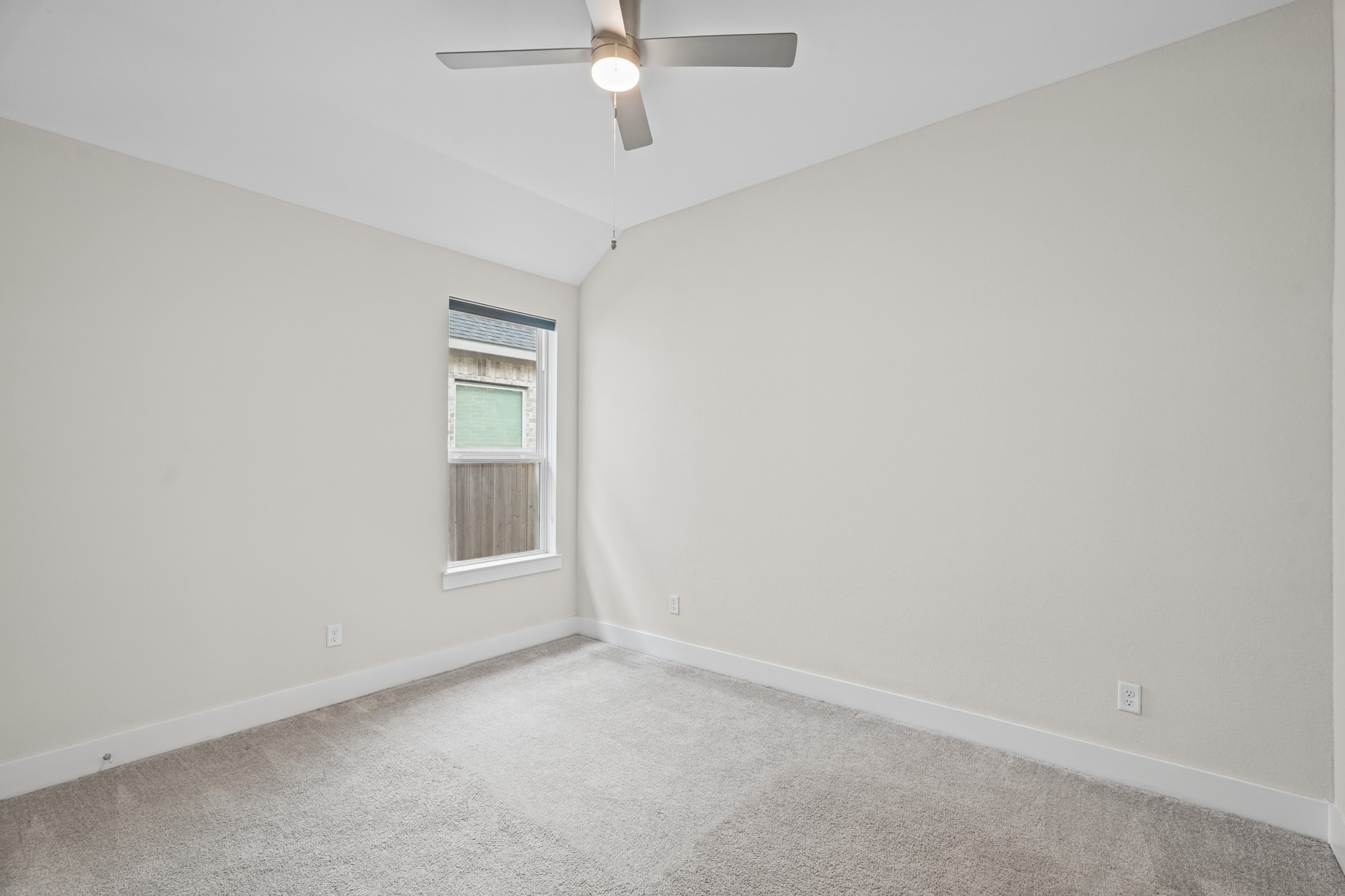 Another secondary bedroom with soft carpet, a ceiling fan and a window bringing in afternoon light - an easy flex space for a guest room, nursery or home gym setup.