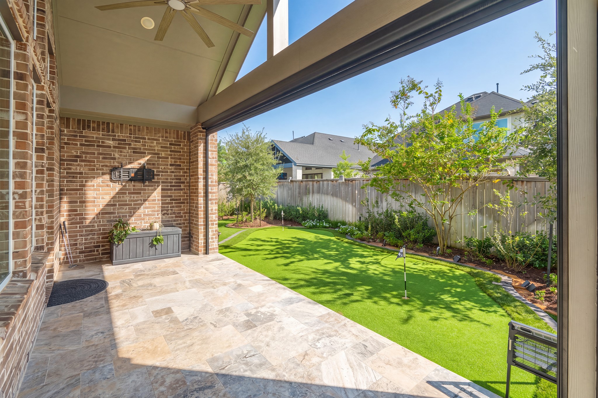Brick columns and a tiled floor define the covered outdoor living area, which connects directly to the main living space for effortless indoor-outdoor entertaining.