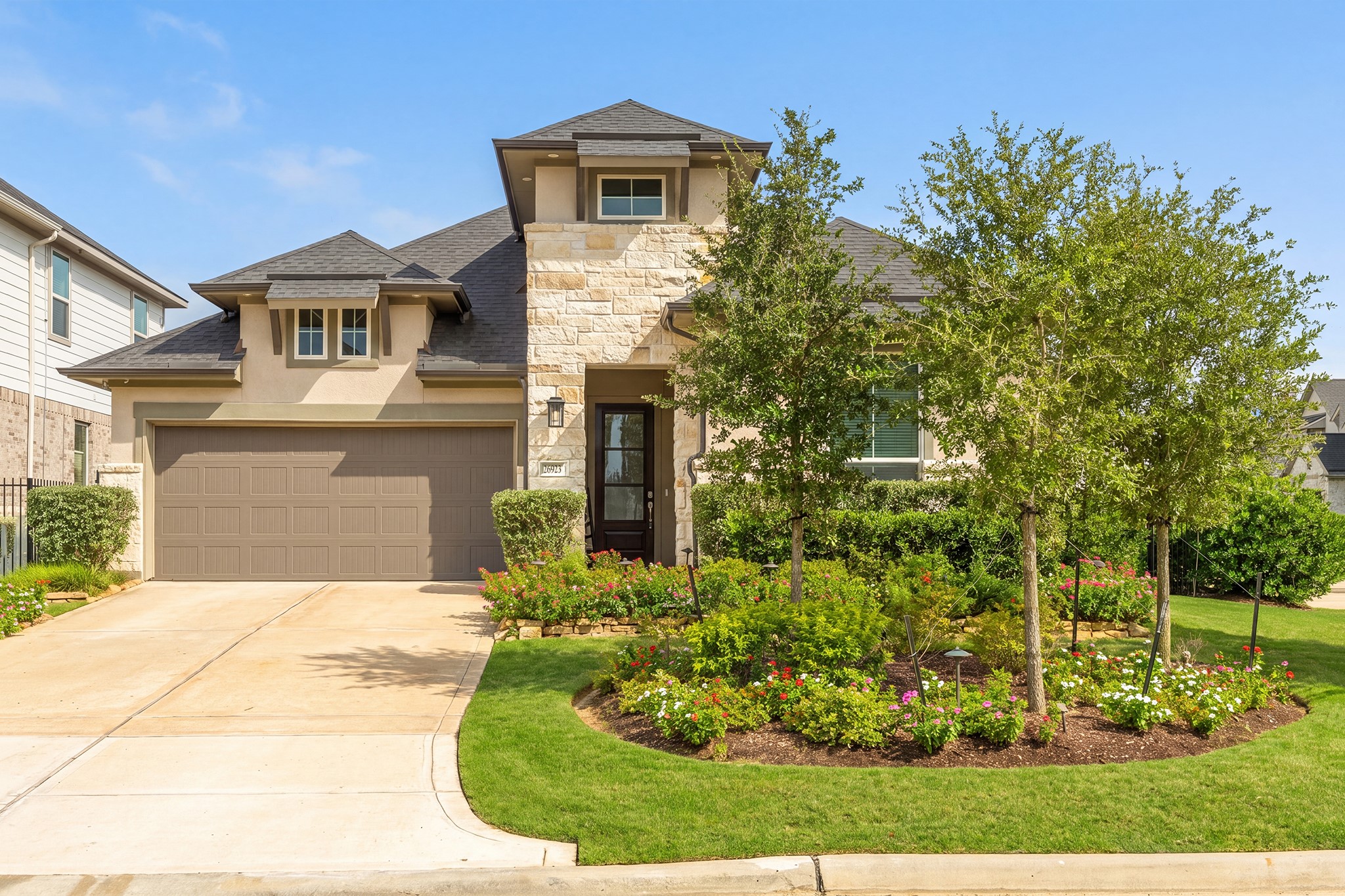 Angled view of the front elevation highlighting the covered entry, layered gable rooflines and mature foundation planting that give the home real curb appeal from the street.