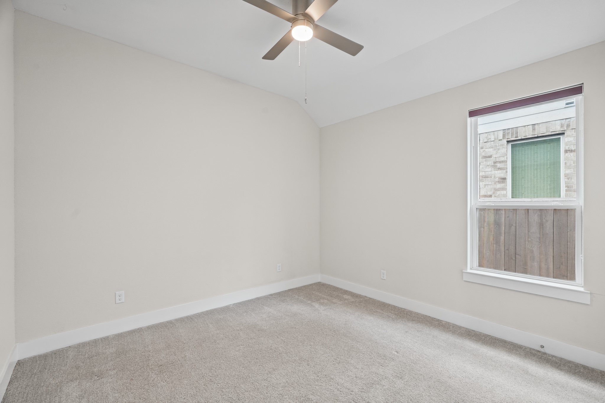 Secondary bedroom with soft carpet, a ceiling fan and a window overlooking the yard, sized comfortably for a queen bed, nightstands and a dresser with room left over.