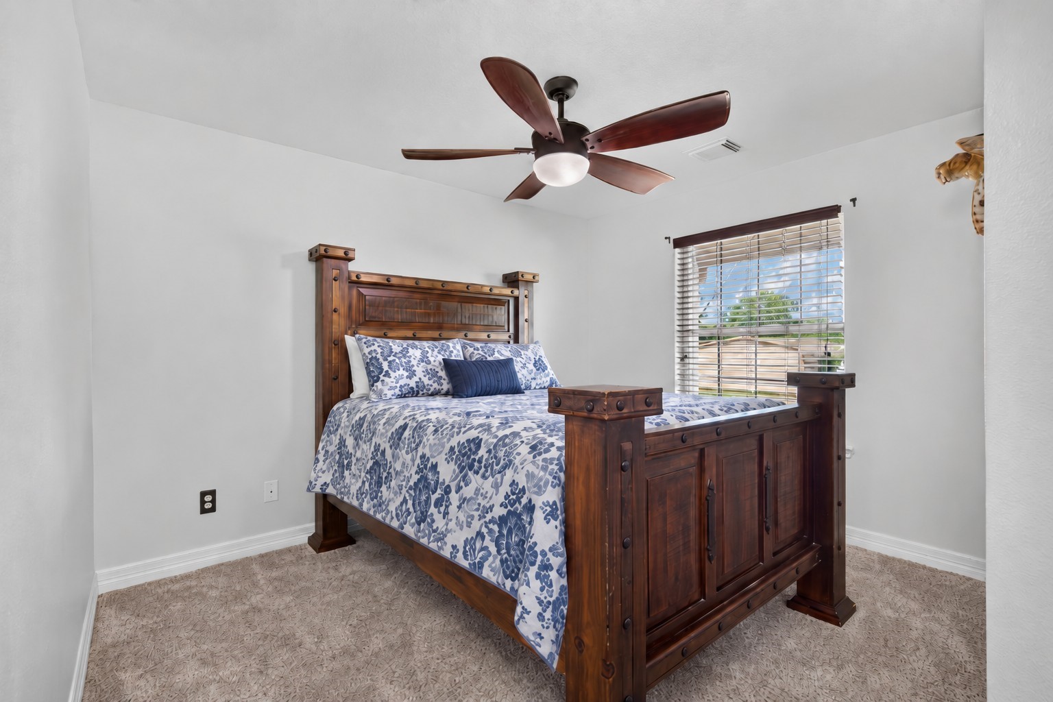 Spacious second bedroom featuring an upgraded ceiling fan and front-yard pond views.
