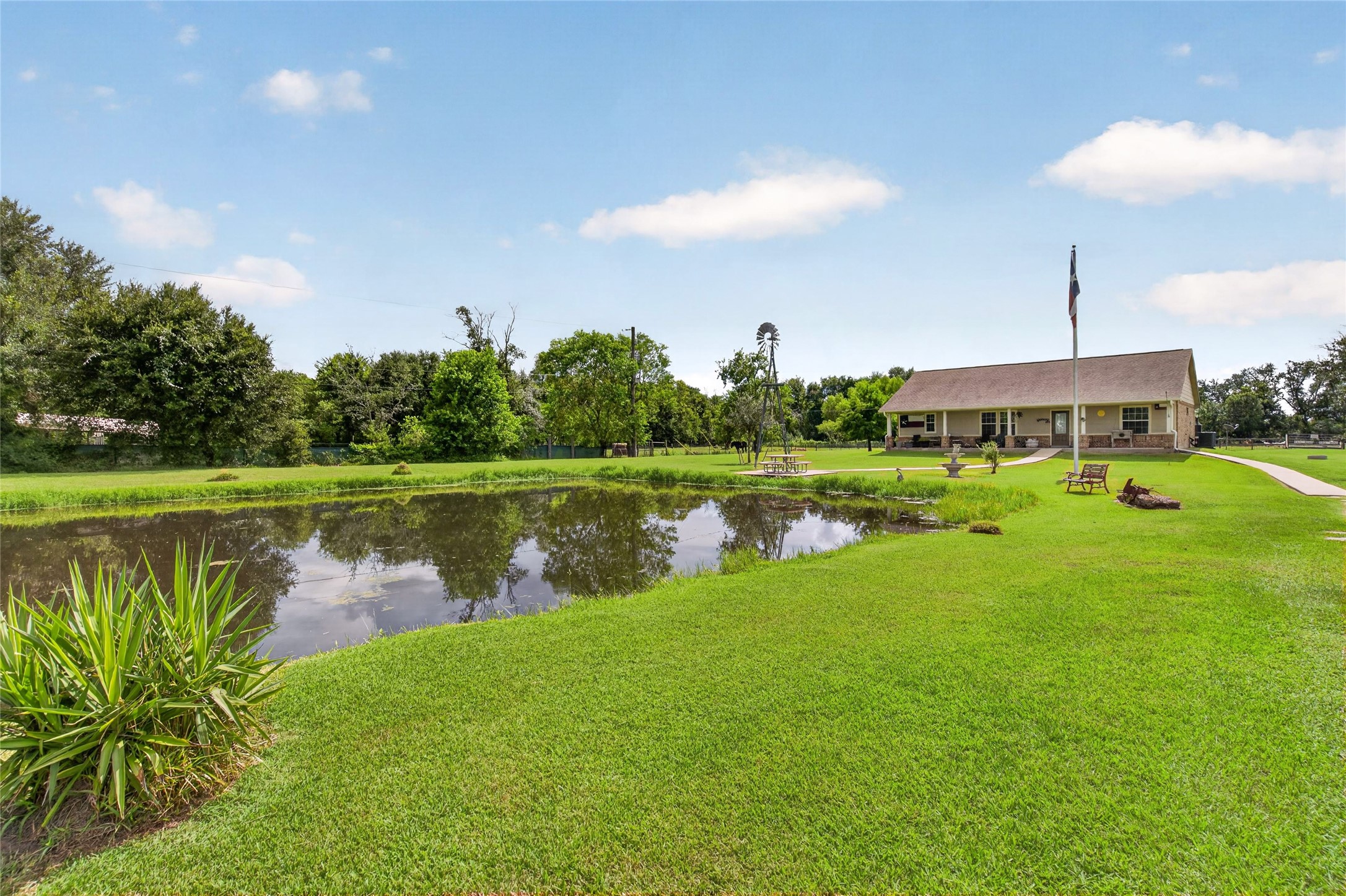 Beautiful pond setting surrounded by mature trees, open green space, and tranquil country views.