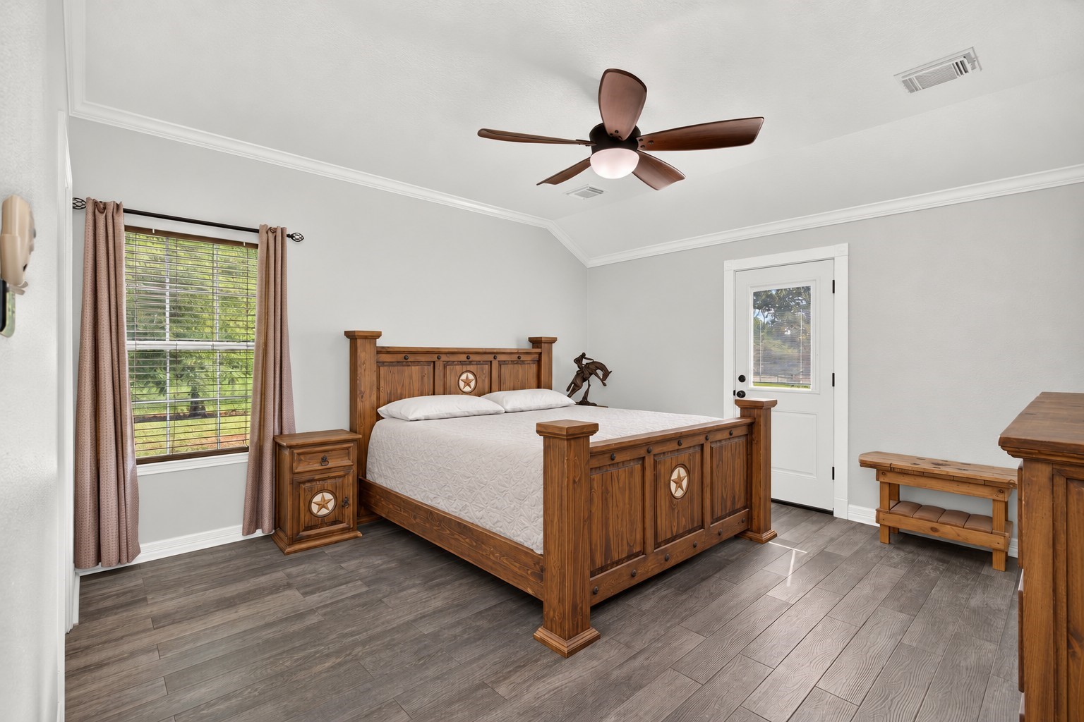 Spacious primary bedroom with a high ceiling, crown molding, and wood-look tile flooring. Spacious primary bedroom with a high ceiling, crown molding, and wood-look tile flooring.