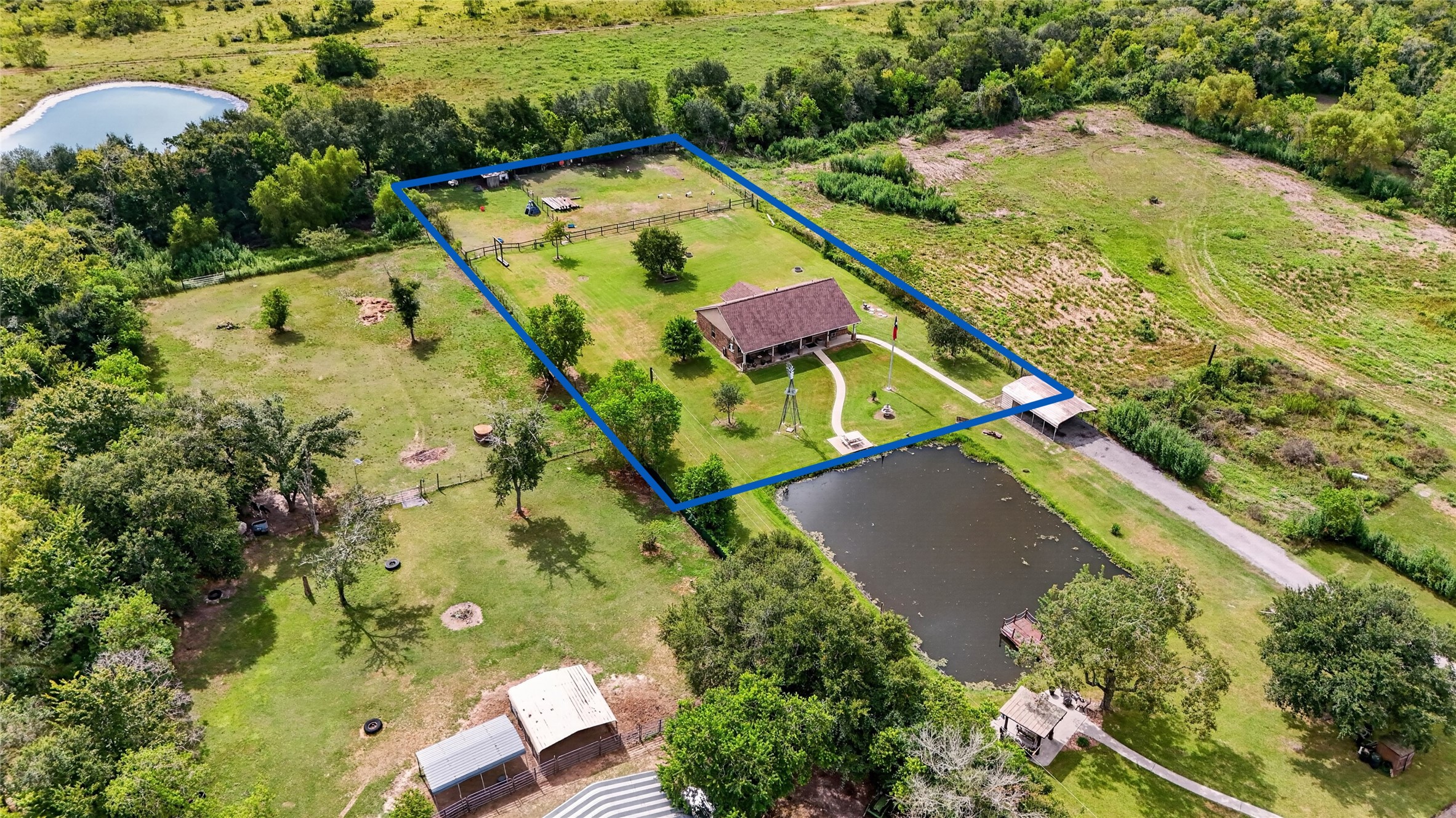 Aerial view showcasing the property boundaries, expansive grounds, mature trees, fenced areas, and neighboring pond views. Aerial view showcasing the property boundaries, expansive grounds, mature trees, fenced areas, and neighboring pond views.