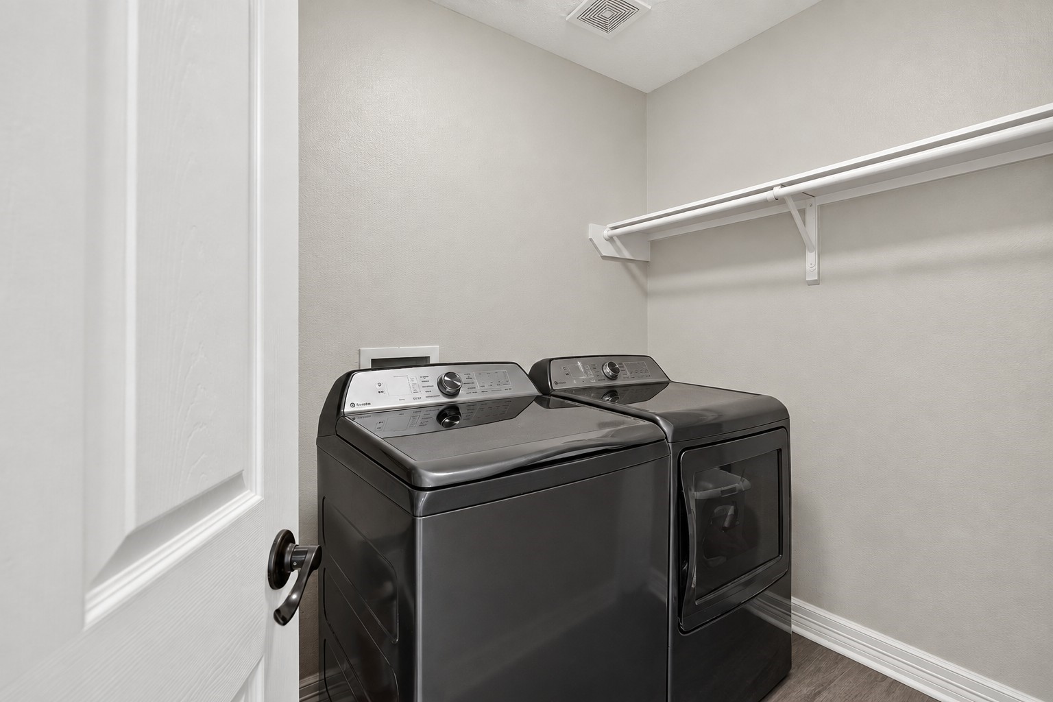Generous laundry room offering built-in storage and hanging space for added functionality.