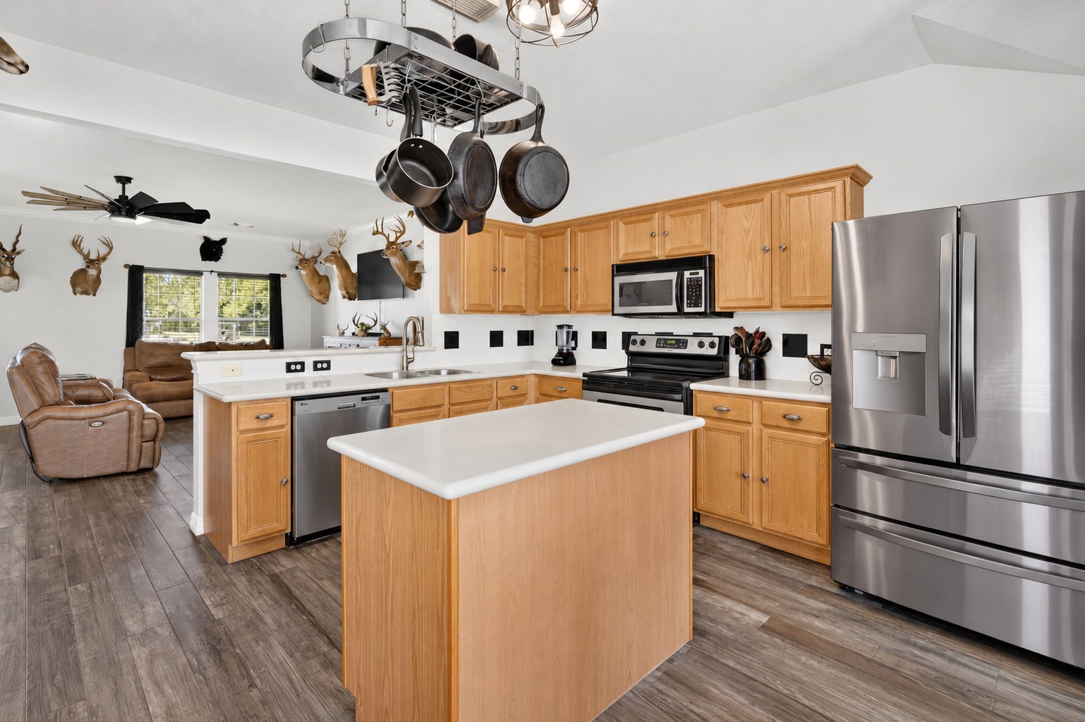 Bright kitchen with a generous island, Corian countertops, hanging pot rack, and an open view into the living area. Bright kitchen with a generous island, Corian countertops, hanging pot rack, and an open view into the living area.