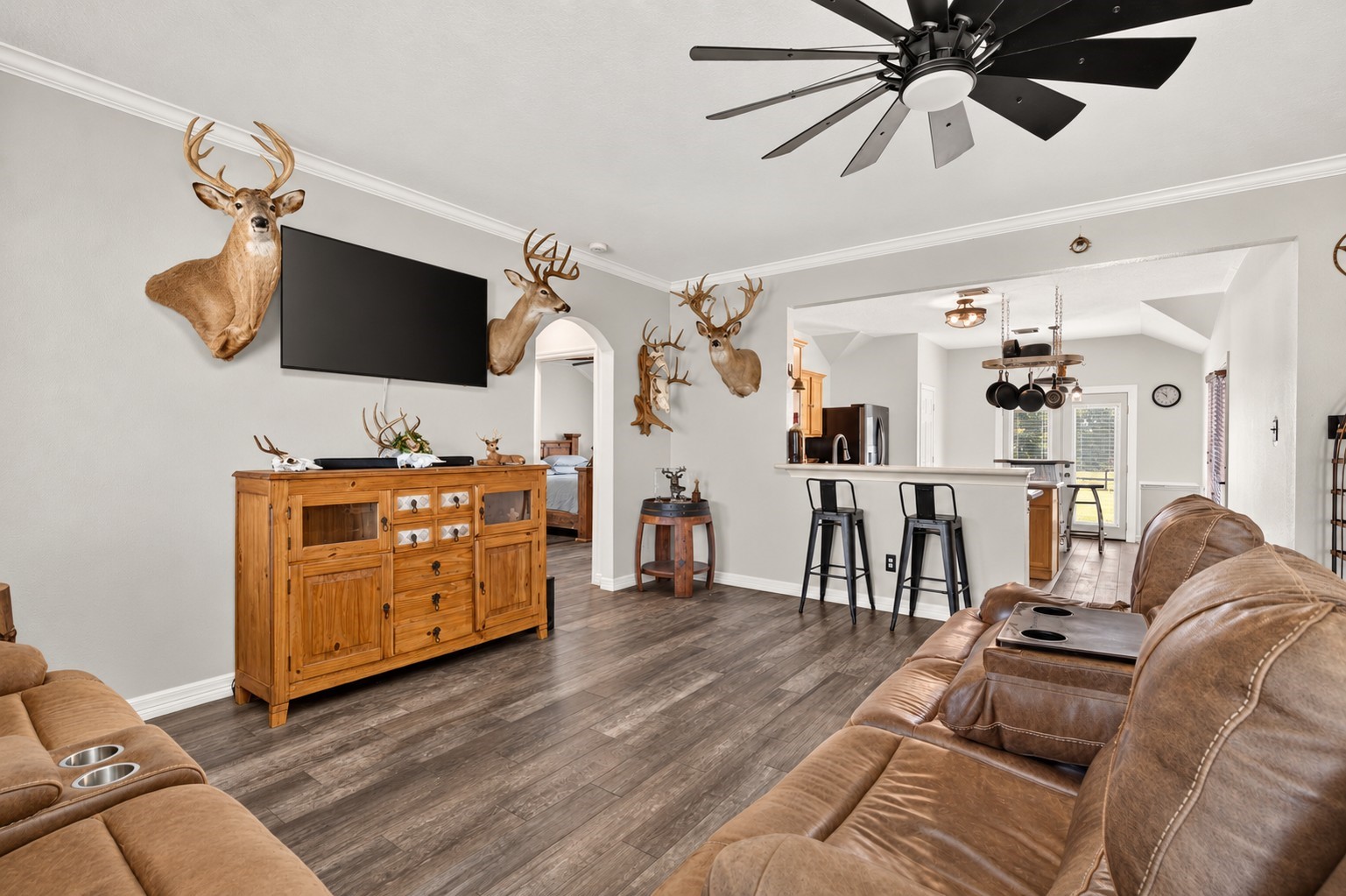 Living room with crown molding, an oversized ceiling fan, and an open view into the kitchen and breakfast area. Living room with crown molding, an oversized ceiling fan, and an open view into the kitchen and breakfast area.