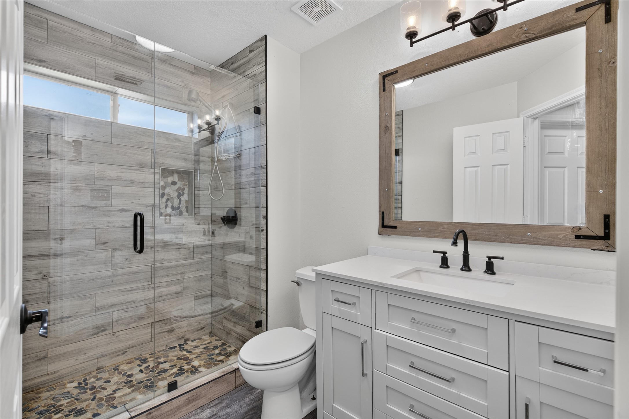 Guest bath with an updated custom shower, tile surround, frameless glass door, and modern vanity.
