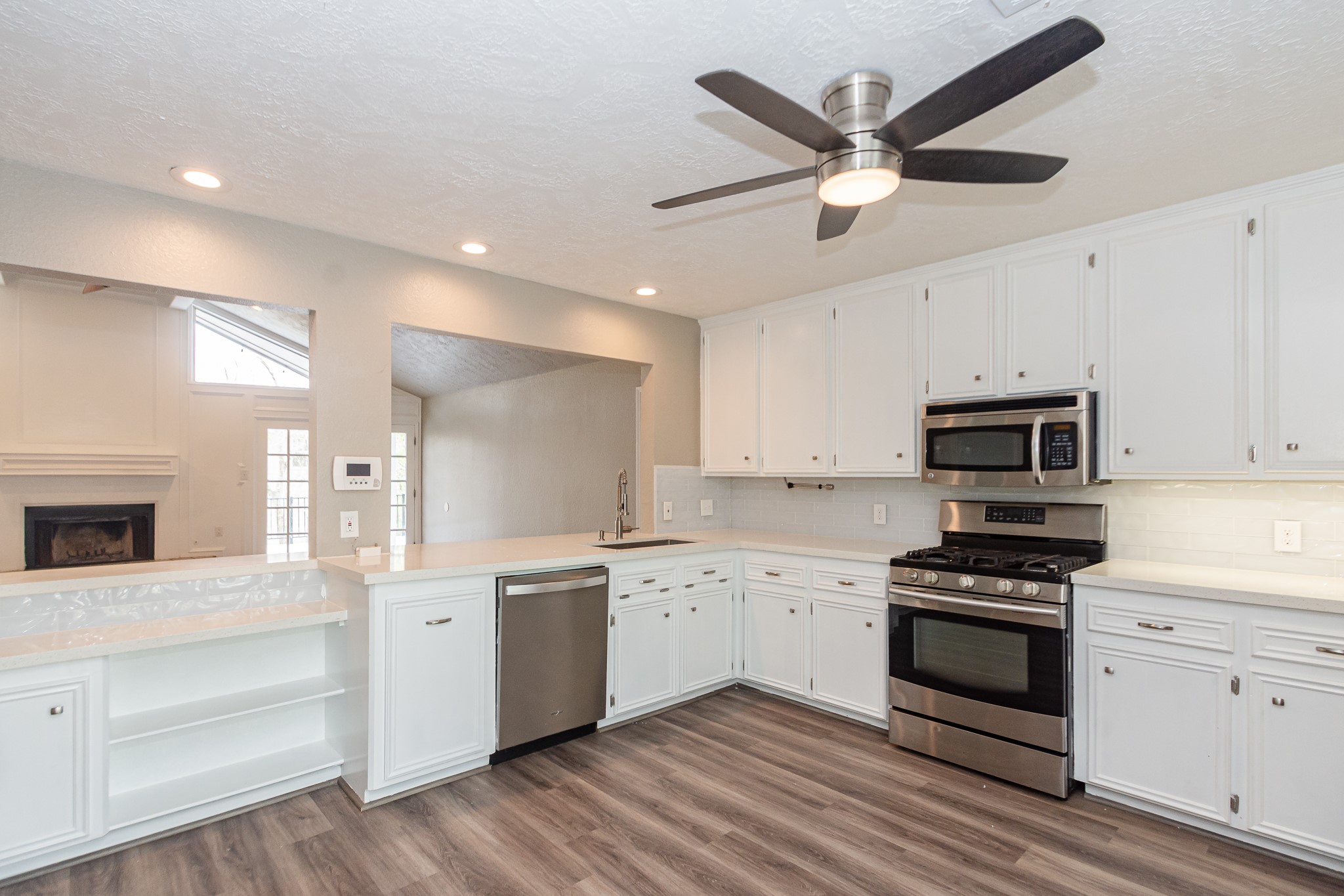 White quartz countertops are paired with a deep single-basin sink and a sleek pull-down faucet. Under cabinet lighting.