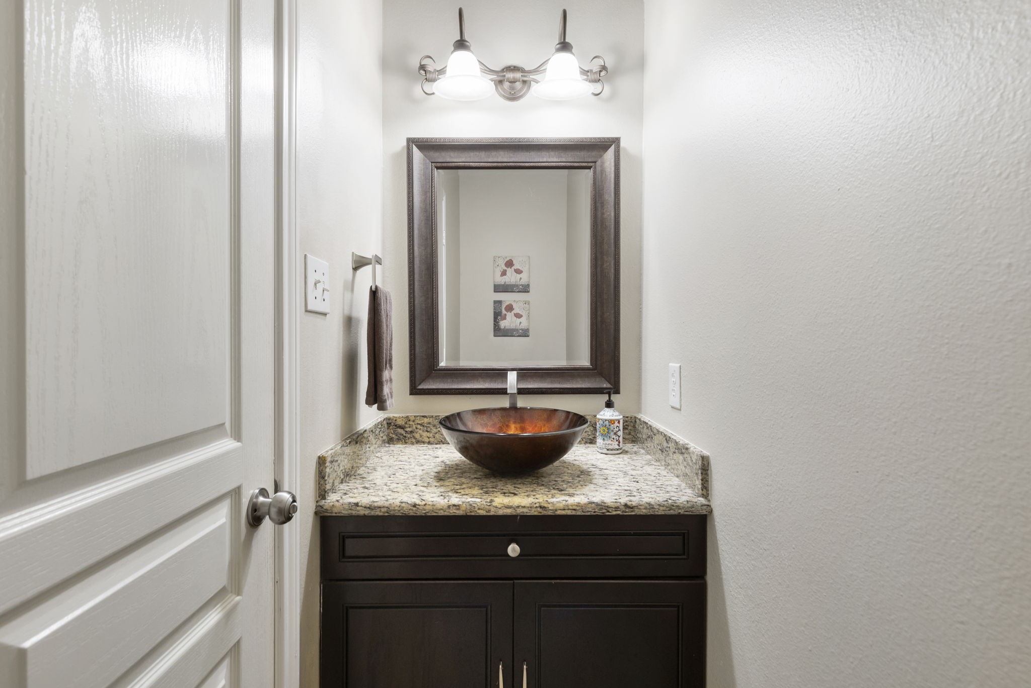 The conveniently located first-floor half bathroom features granite countertops and a stylish vessel sink, perfect for guests.
