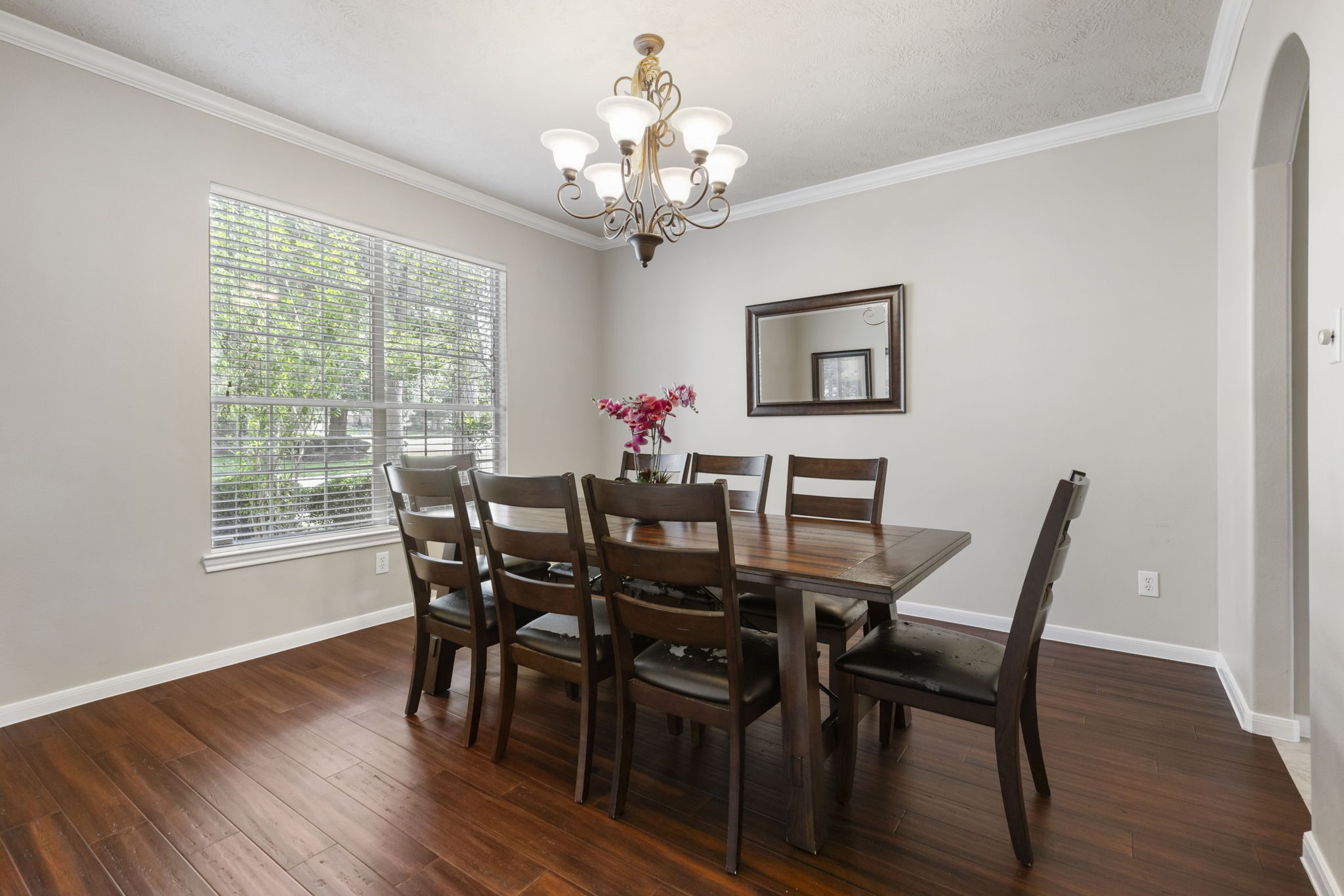Natural light fills the spacious dining room, featuring beautiful wood flooring, crown molding, and plenty of room to gather around the table