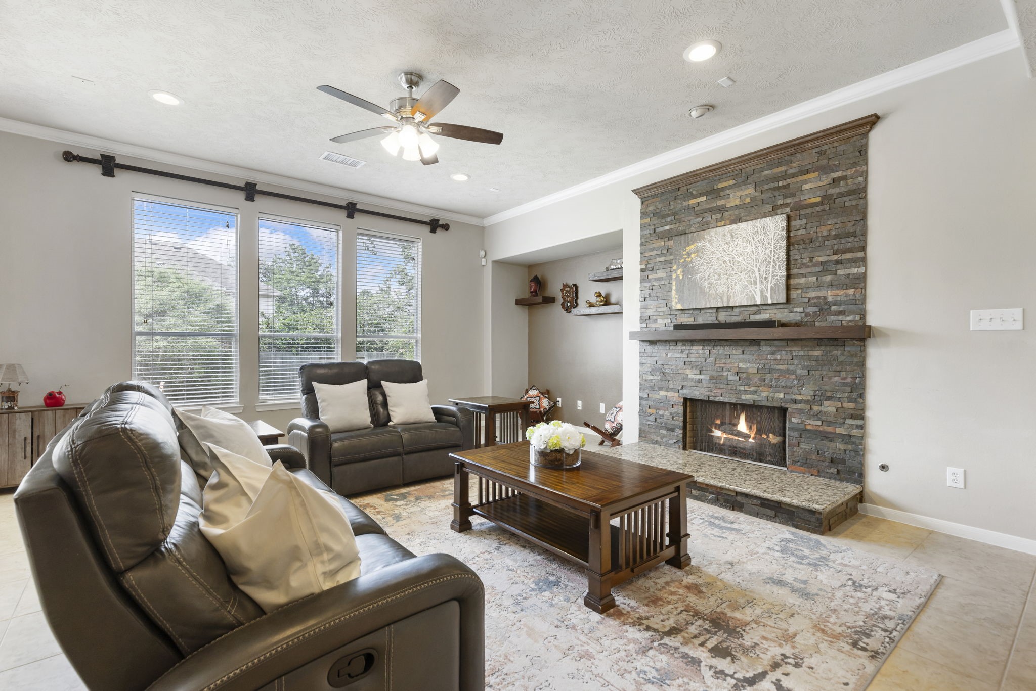 The inviting living room features large windows, a beautiful floor-to-ceiling stone fireplace, and plenty of space to gather and unwind.