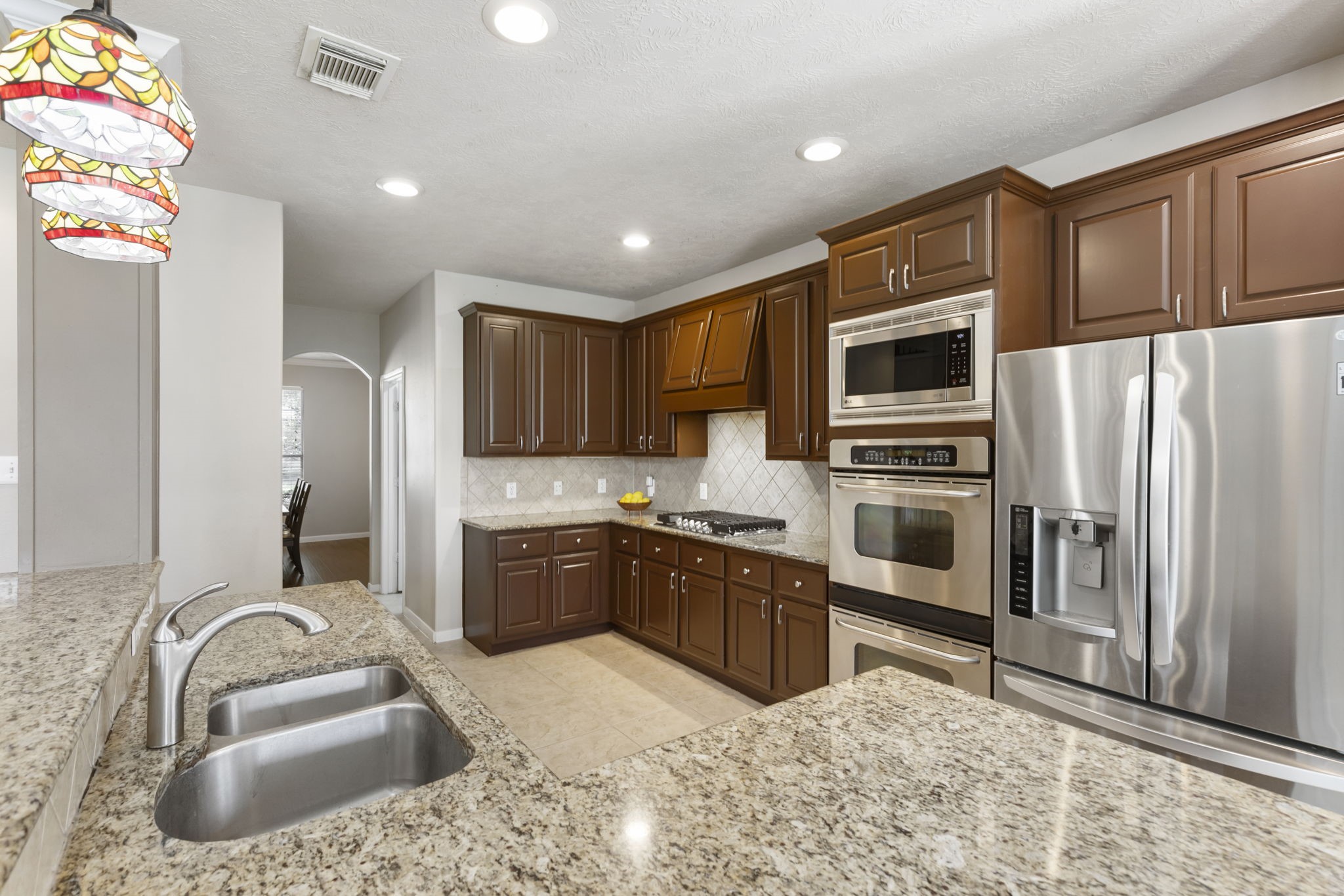 The spacious island kitchen features granite countertops, stainless steel appliances, double ovens, and abundant cabinetry for both storage and functionality.