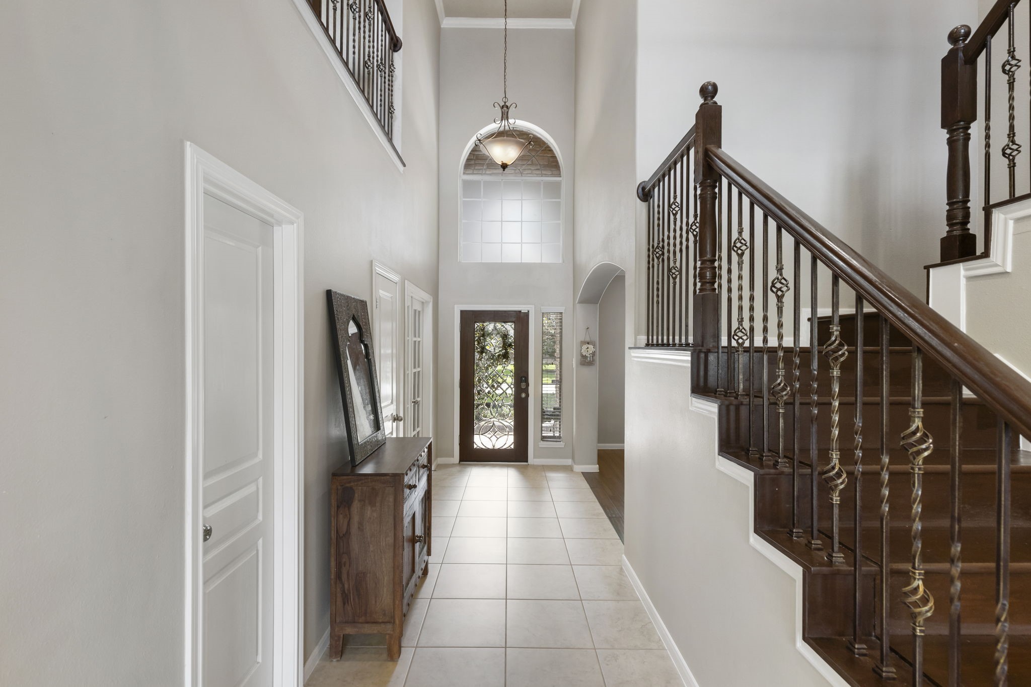 The grand foyer showcases elegant details including a wrought iron staircase, high ceilings, and timeless character that makes a lasting first impression.