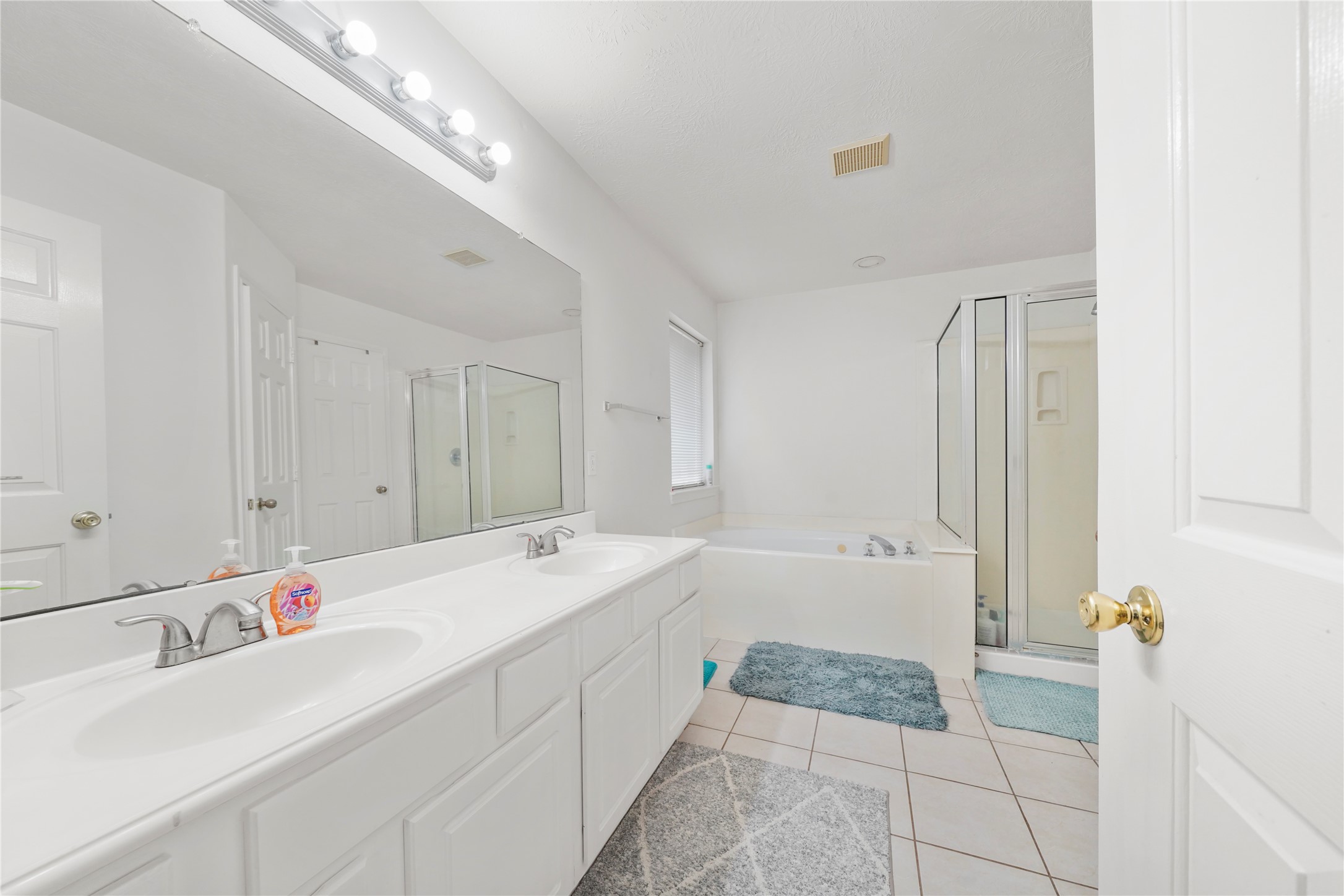 The primary bath begins with an extended dual-sink vanity, bringing useful counter space and storage to the everyday routine.