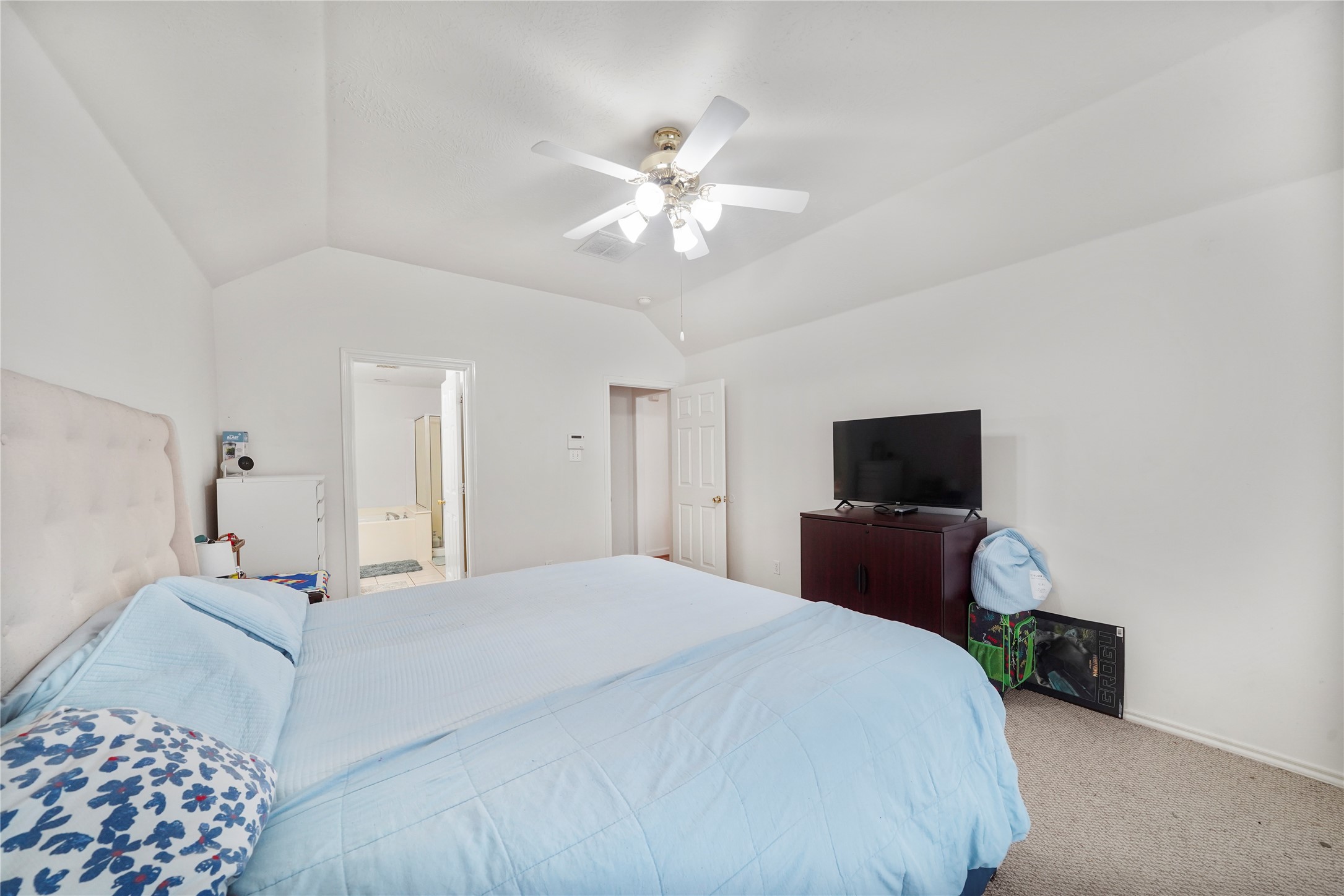 Another view of the primary bedroom captures its peaceful scale and flexible wall space for a dresser, media console, or reading chair.