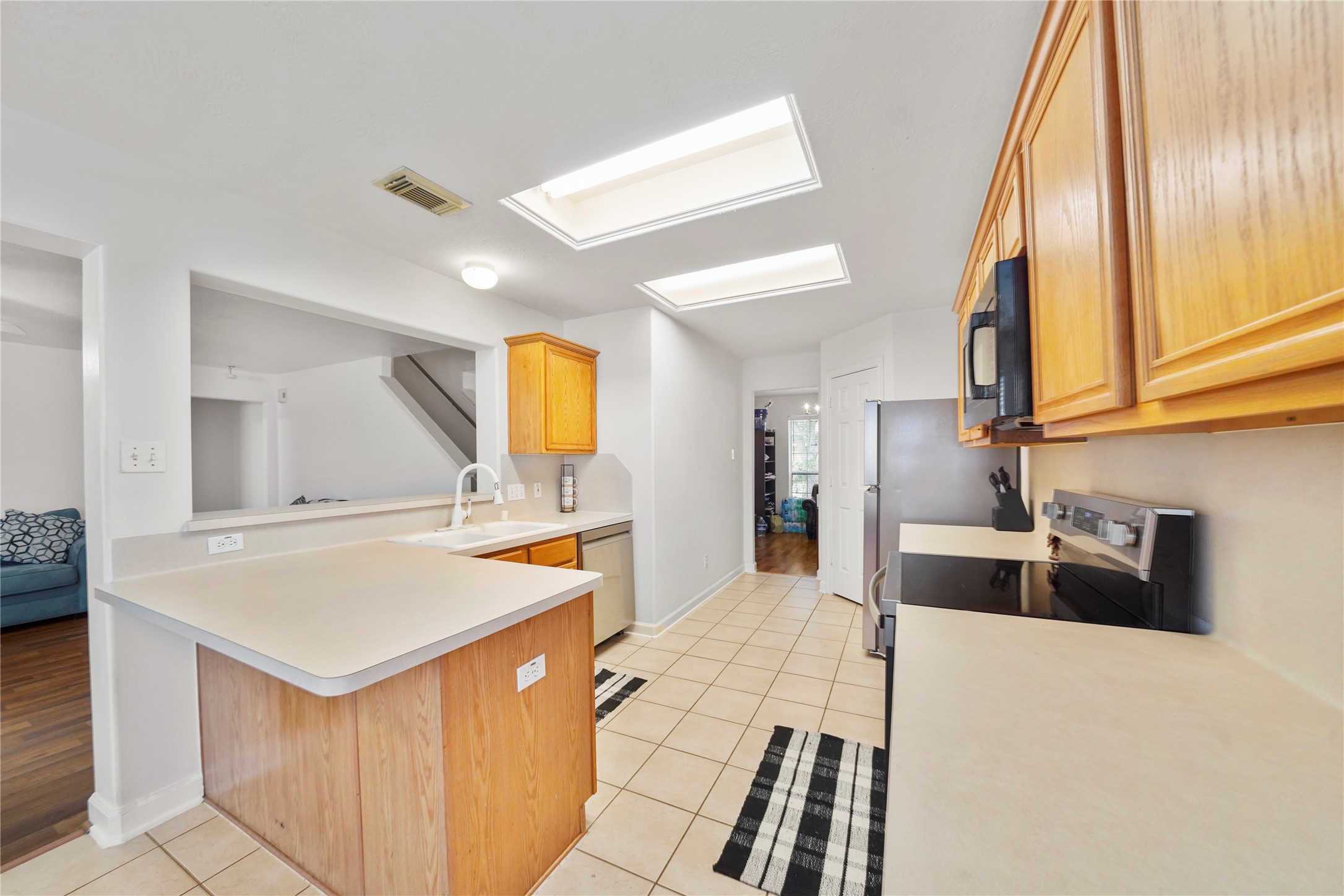 Warm cabinetry, a broad serving peninsula, and open sightlines make the kitchen practical and inviting; the range, over-the-range microwave, stainless steel refrigerator and dishwasher were replaced in August 2026. Warm cabinetry, a broad serving peninsula, and open sightlines make the kitchen practical and inviting; the range, over-the-range microwave, stainless steel refrigerator and dishwasher were replaced in August 2026.