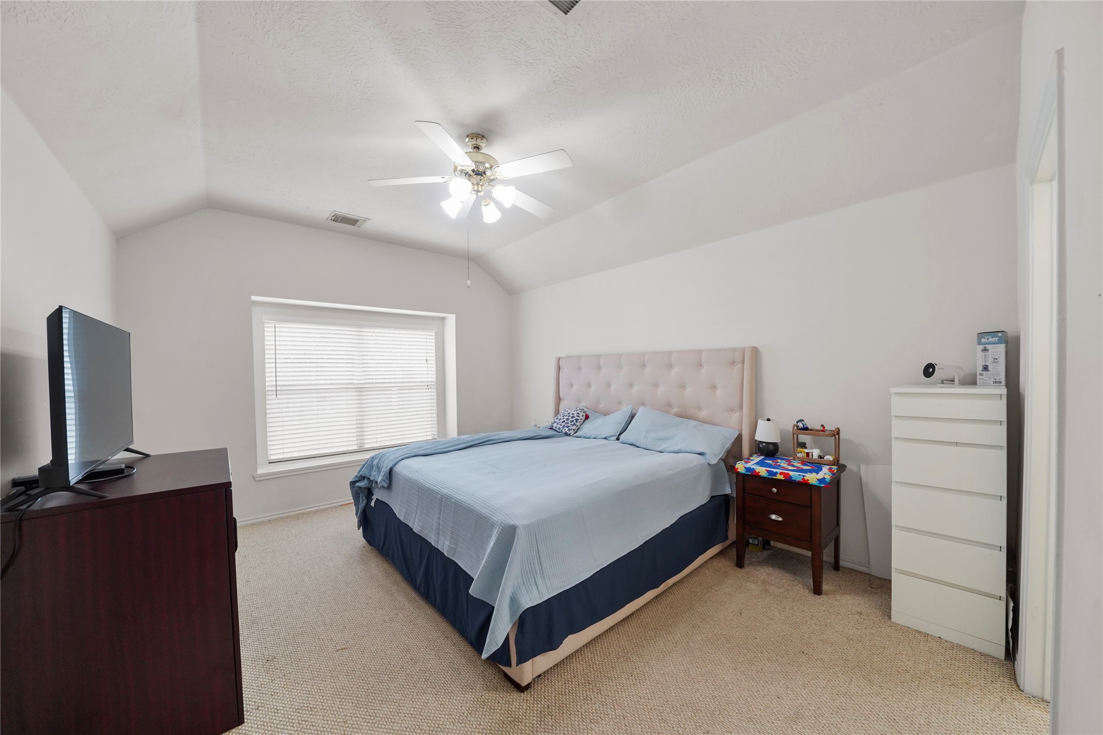 The primary retreat offers room to settle in comfortably, with a soft neutral palette, ceiling fan, and space for a full furniture arrangement.