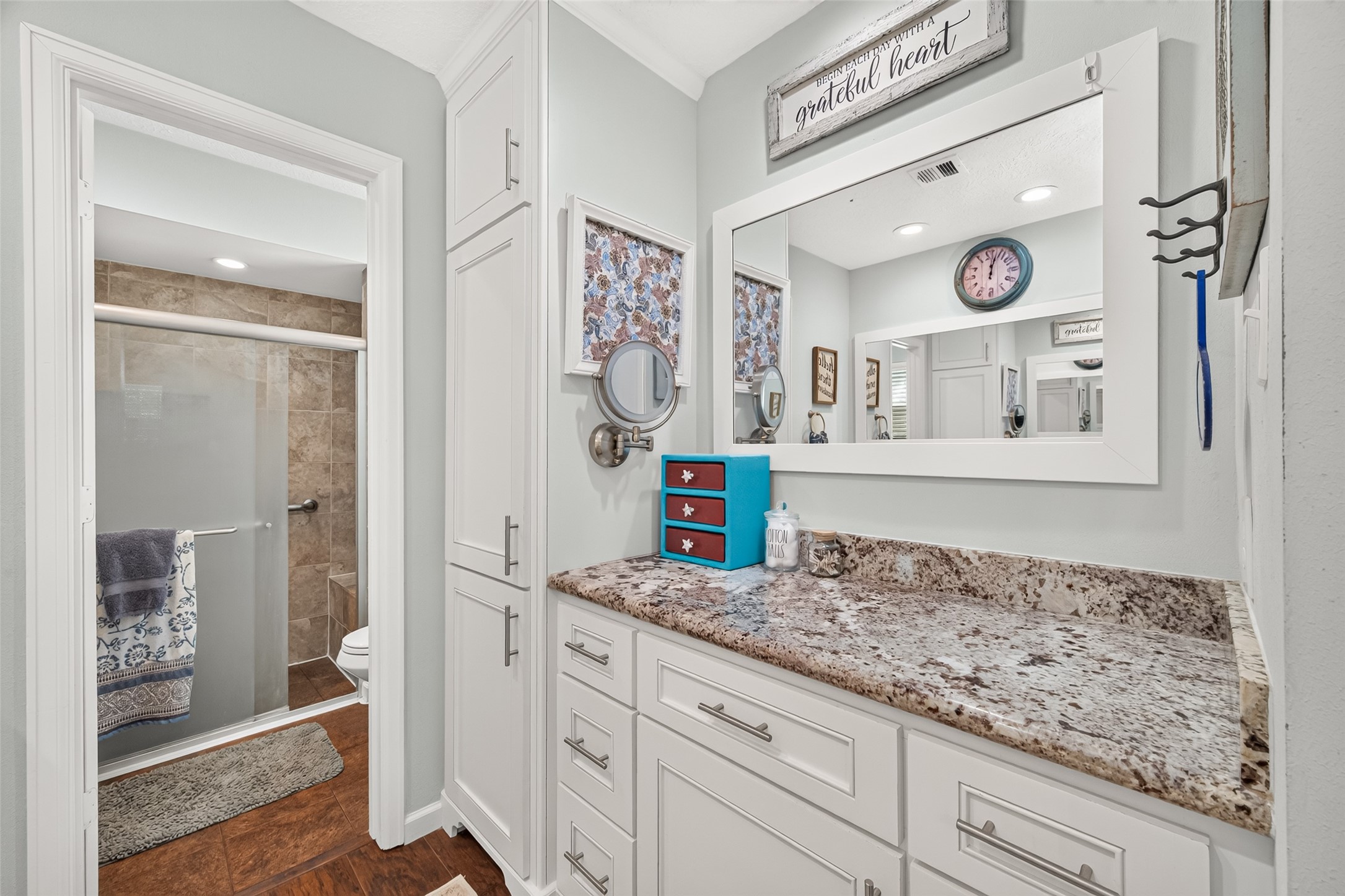 ANOTHER VIEW OF THE VANITY AREA IN THE PRIMARY BATHROOM; LOTS OF DRAWERS AND CABINET SPACE; WALK IN SHOWER WITH SEATING INSIDE; A WINDOW FOR NATURAL LIGHT