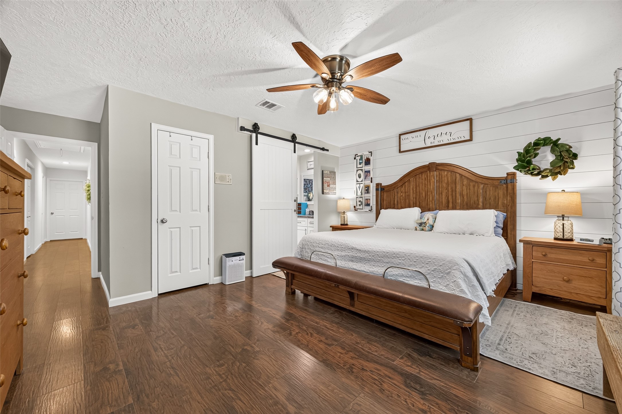 ANOTHER VIEW OF THE PRIMARY BEDROOM; WE ADDED THE SINGLE CUSTOM BUILT BARN DOOR TO CLOSE WHEN SOMEONE IS IN THE BATHROOM SINK AND VANITY AREA; THE VIEW OF THE HALLWAY LEADING TO THE OTHER SECONDARY BEDROOMS AND GUEST BATHROOM; THE CLOSED DOOR IS THE PRIMARY BEDROOM CLOSET; WE MATCHED THE BARN DOOR WITH ALL HANDLES MATCHING THE REST OF THE CABINETS IN THE HOME