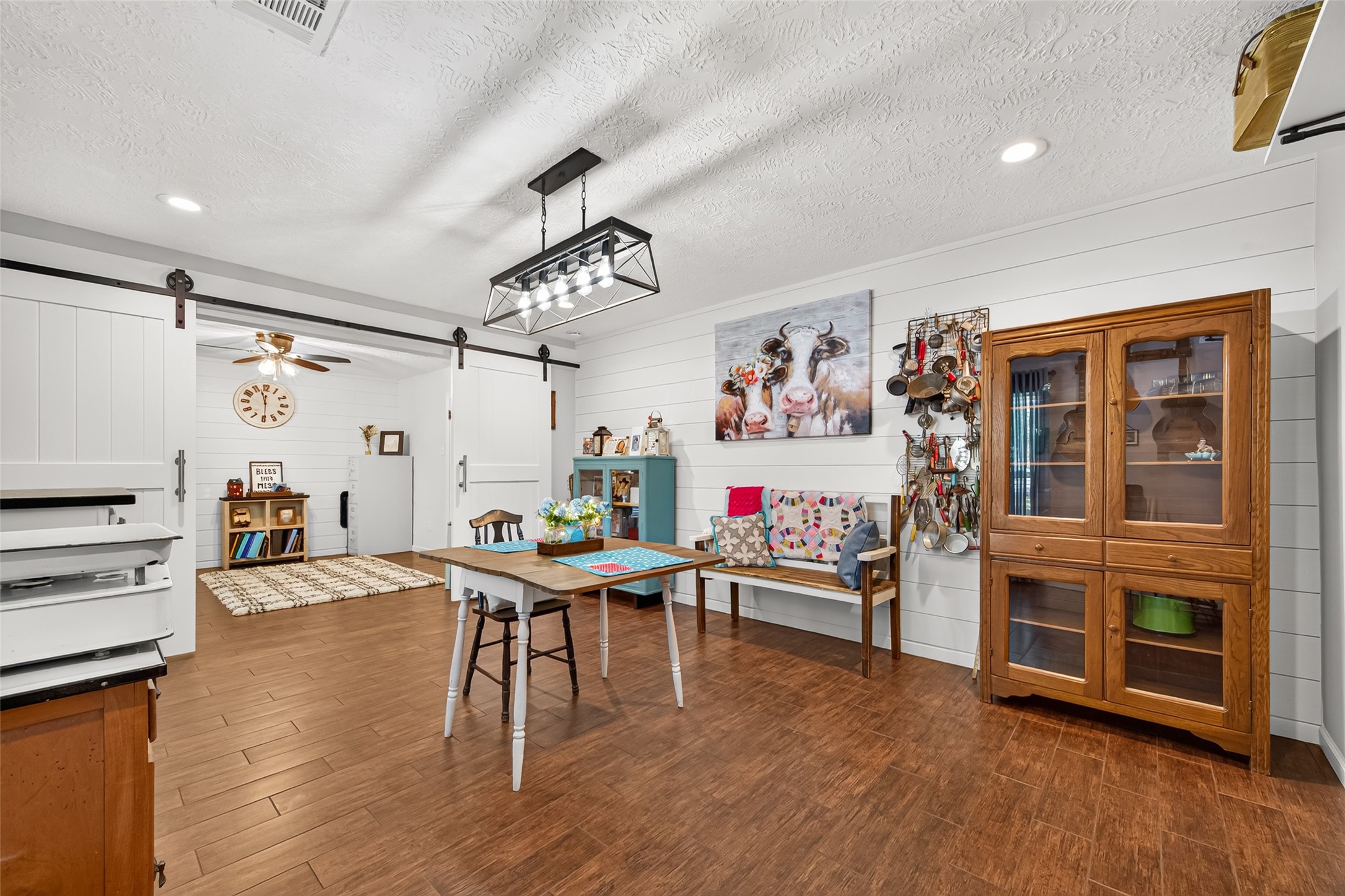 LOOK AT THE BEAUTIFUL WOOD LIKE TILE FLOORS (GROUT HAS BEEN RECENTLY RESEALED); THIS IS THE FORMAL DINING ROOM FOR ENJOYING YOUR FAMILY DURING SPECIAL GATHERINGS; ADDED SHIPLAP ACCENT WALL; ADDED A FARMHOUSE LIGHT FIXTURE; ADDED THE SLIDING DOUBLE BARN DOORS BETWEEN THE DINING ROOM AND THE OFFICE; THE DOUBLE BARNS HANDLES MATCHES THE REST OF THE CABINETS IN THE HOME.
