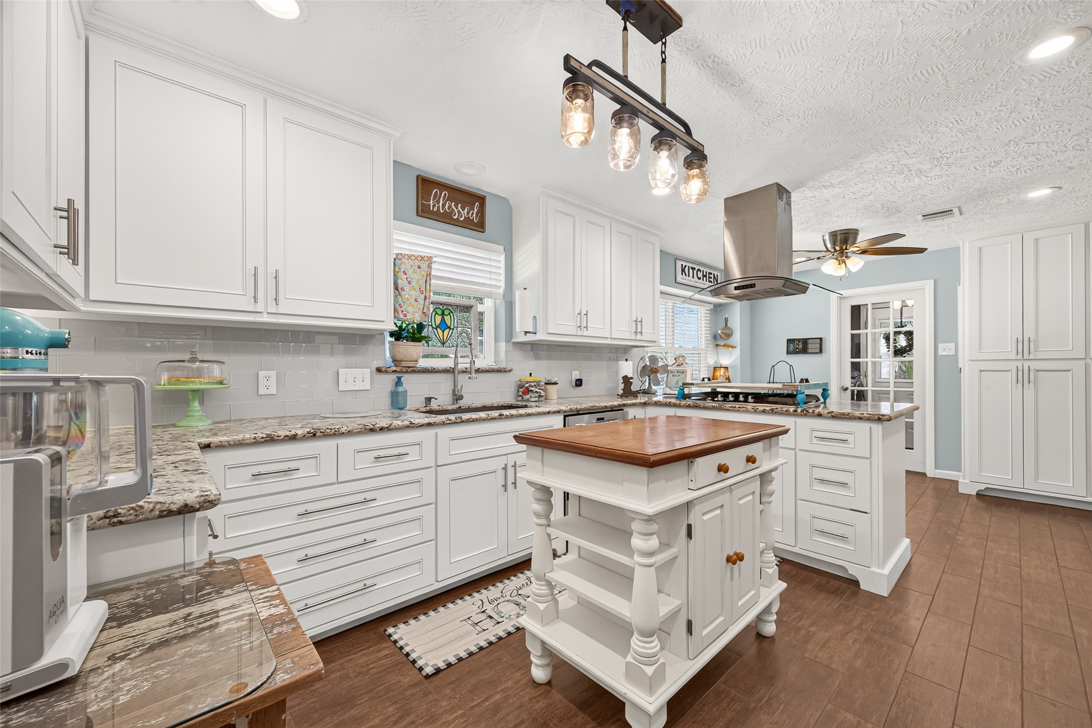 VIEW OF THE SPACIOUS KITCHEN, GRANITE COUNTERTOP, NEW KITCHEN FAUCET, BEAUTIFUL WOOD LOOKING TILE FLOORS, PANTRY TO FAR RIGHT WITH SLIDING OUT DRAWERS AND LOTS OF PANTRY SPACE.