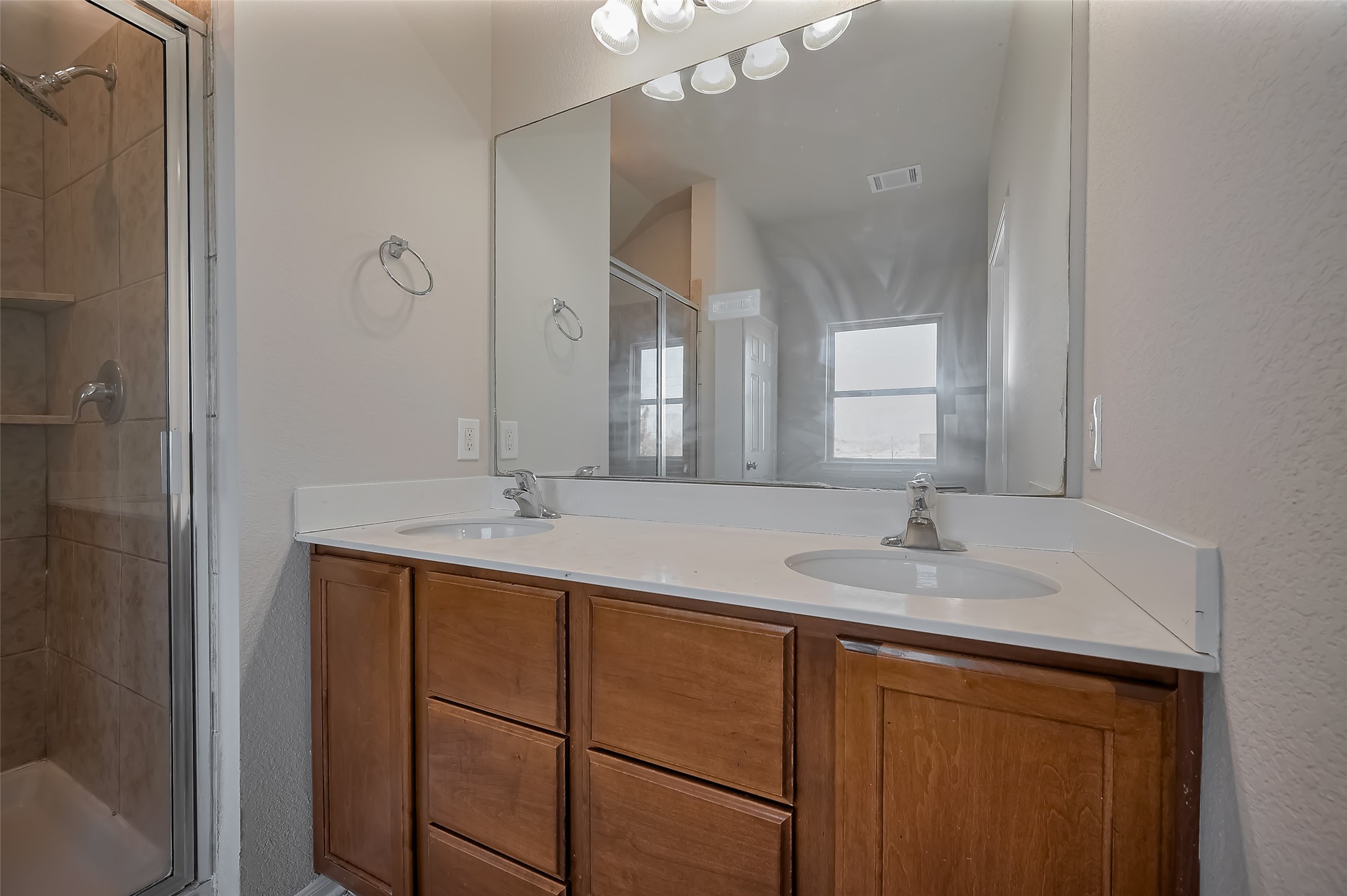 Bathroom features a double vanity with a large mirror and wooden cabinets.
