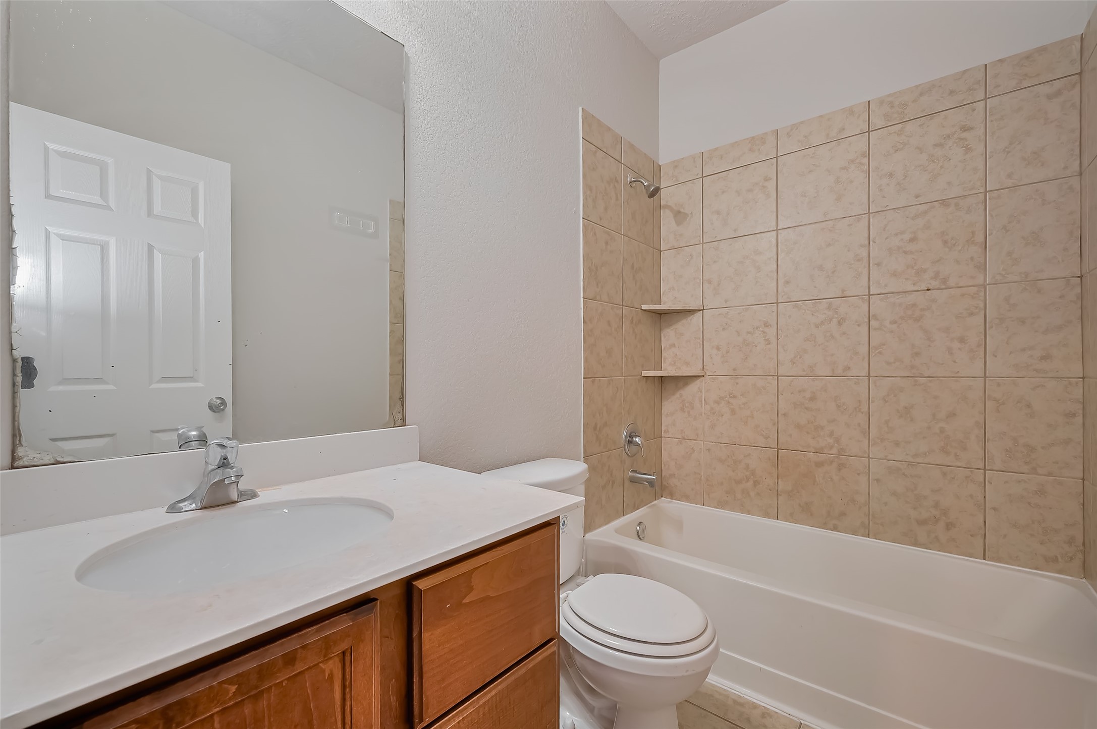 Versatile bathroom featuring a shower-tub combo & wooden vanity.