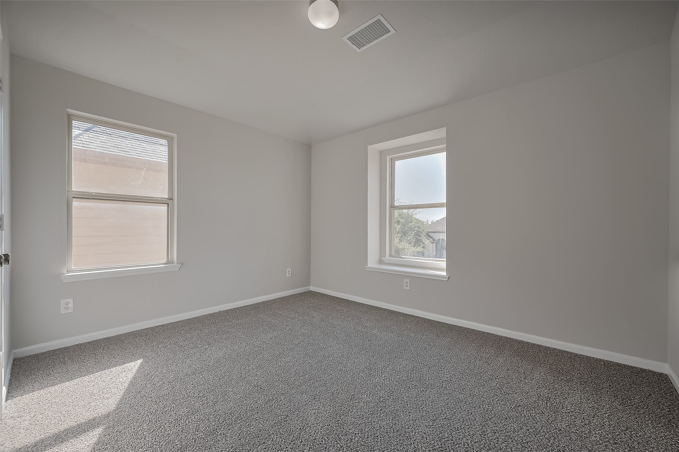 Cozy bedroom features two windows.