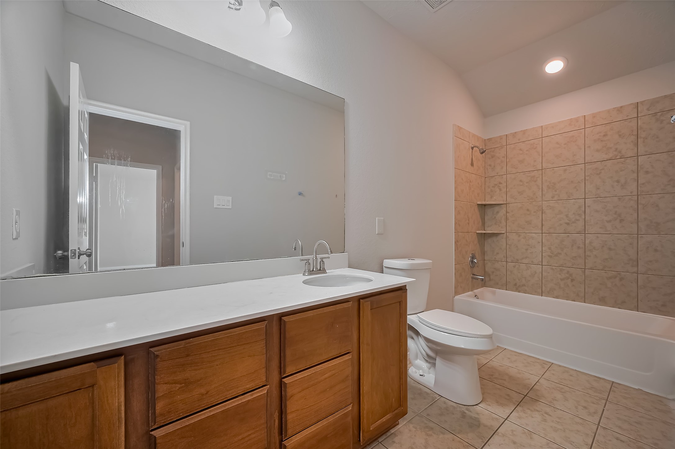 Bathroom features a spacious vanity with a large mirror & wooden cabinetry.