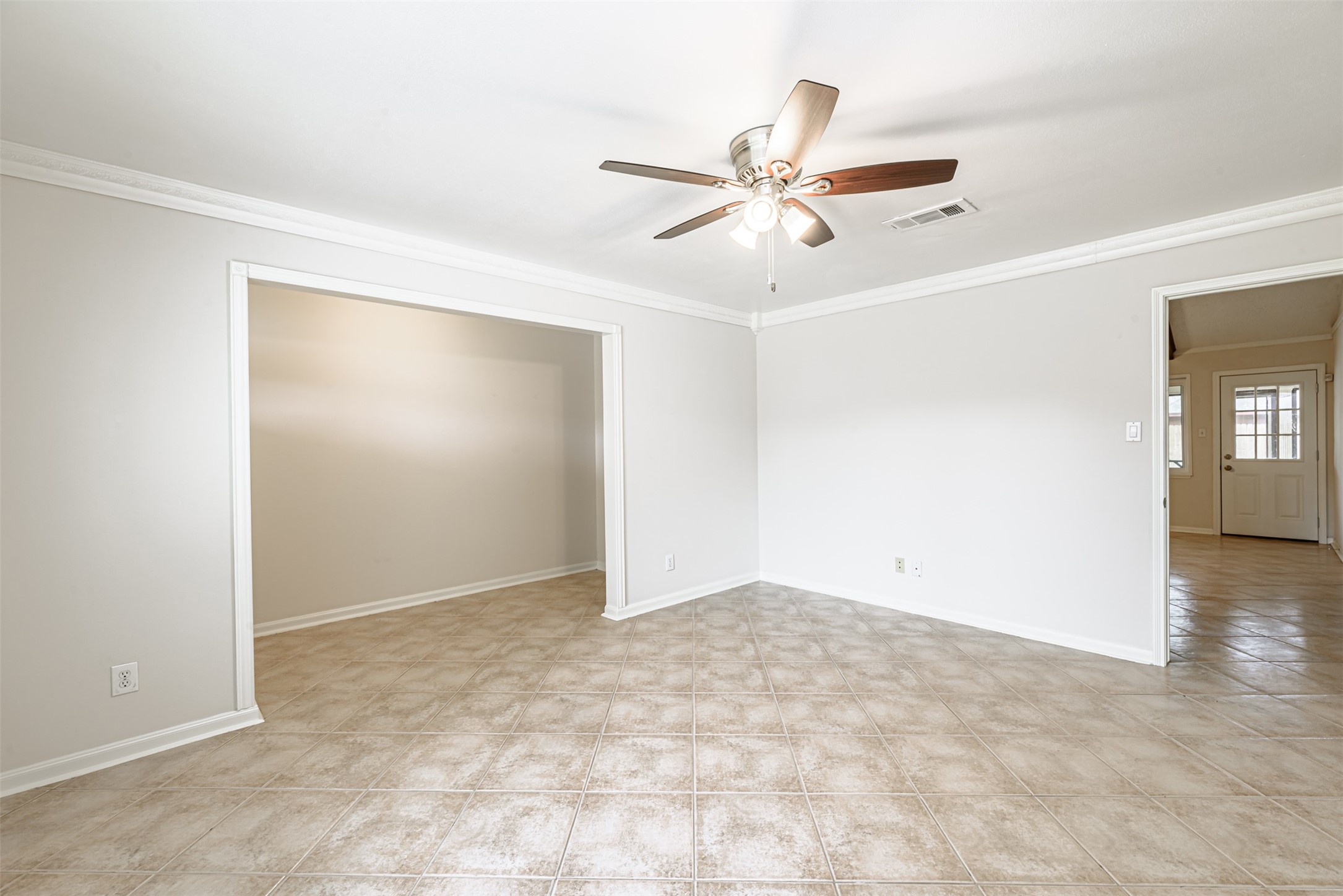 Experience seamless flow from the kitchen to the formal living area on the left and a welcoming exit to the covered patio and backyard on the right, all enhanced by elegant ceramic tile throughout the main living space.