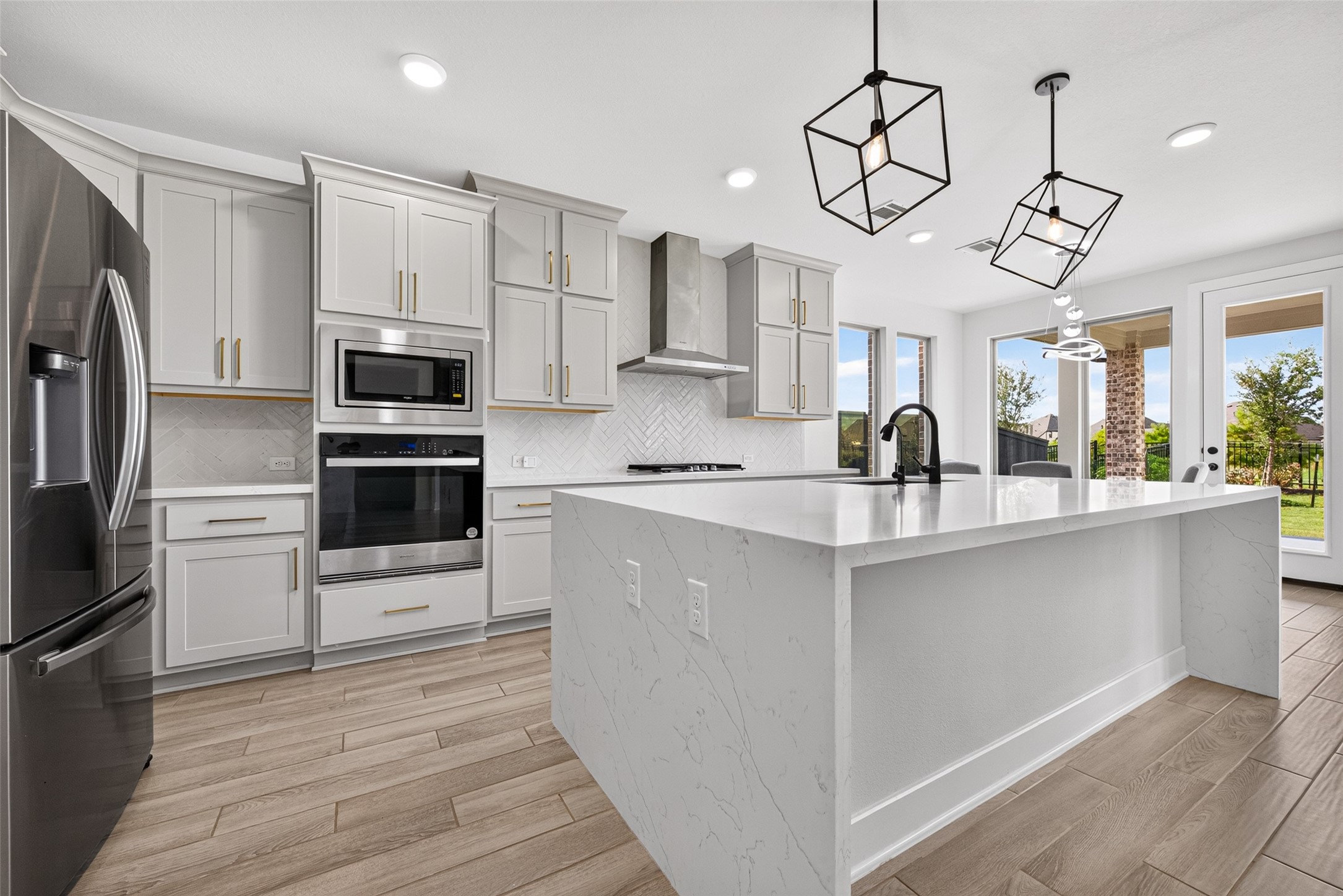 A luxurious chef-inspired kitchen showcasing built-in appliances, a stunning waterfall quartz countertop, and upgraded Shaker-style cabinetry accented with elegant hardware and crown molding, blending timeless design with sophisticated modern appeal