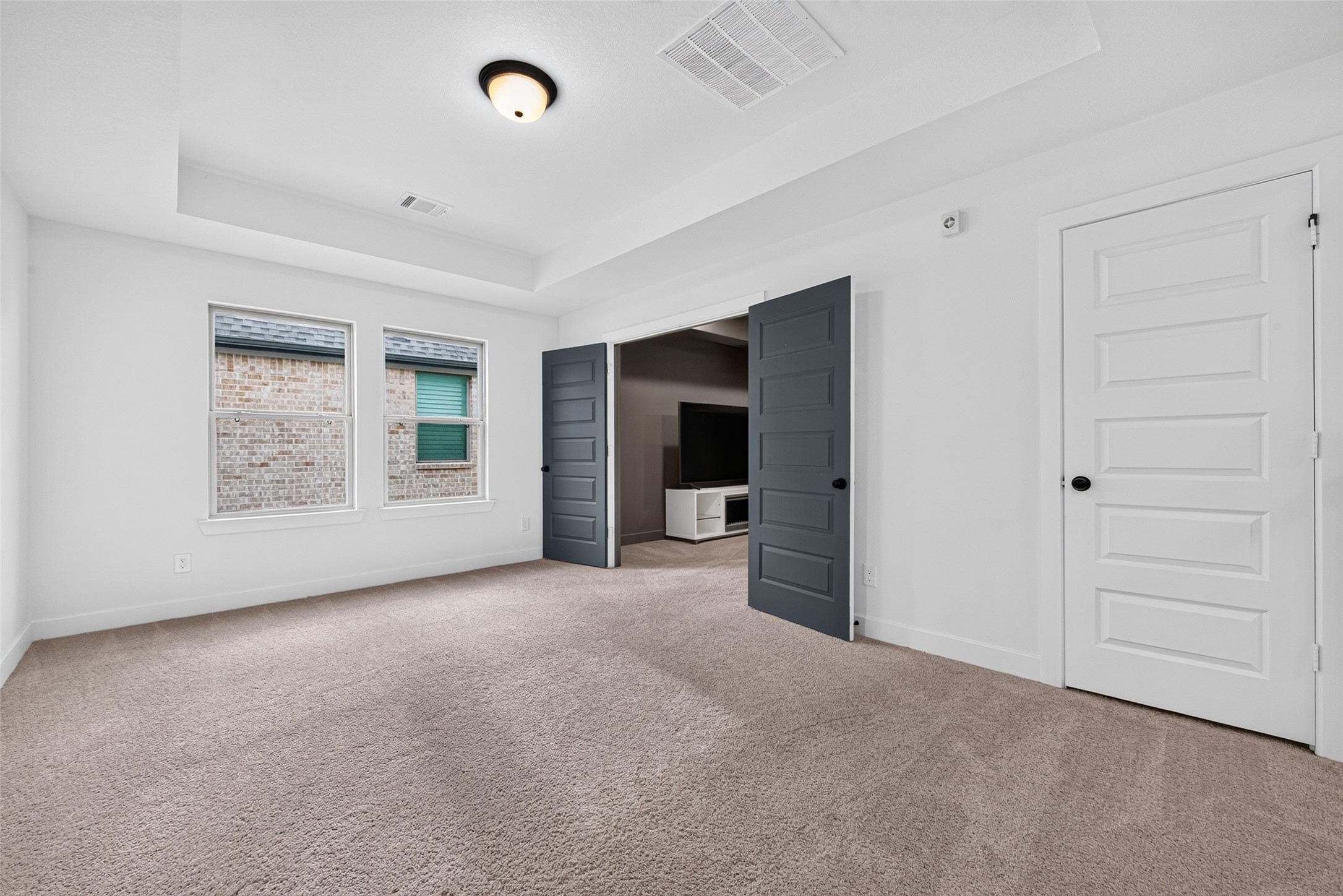 An expansive game room featuring elegant tray ceilings and direct access to the media room, creating an exceptional setting for entertainment, recreation, and memorable gatherings