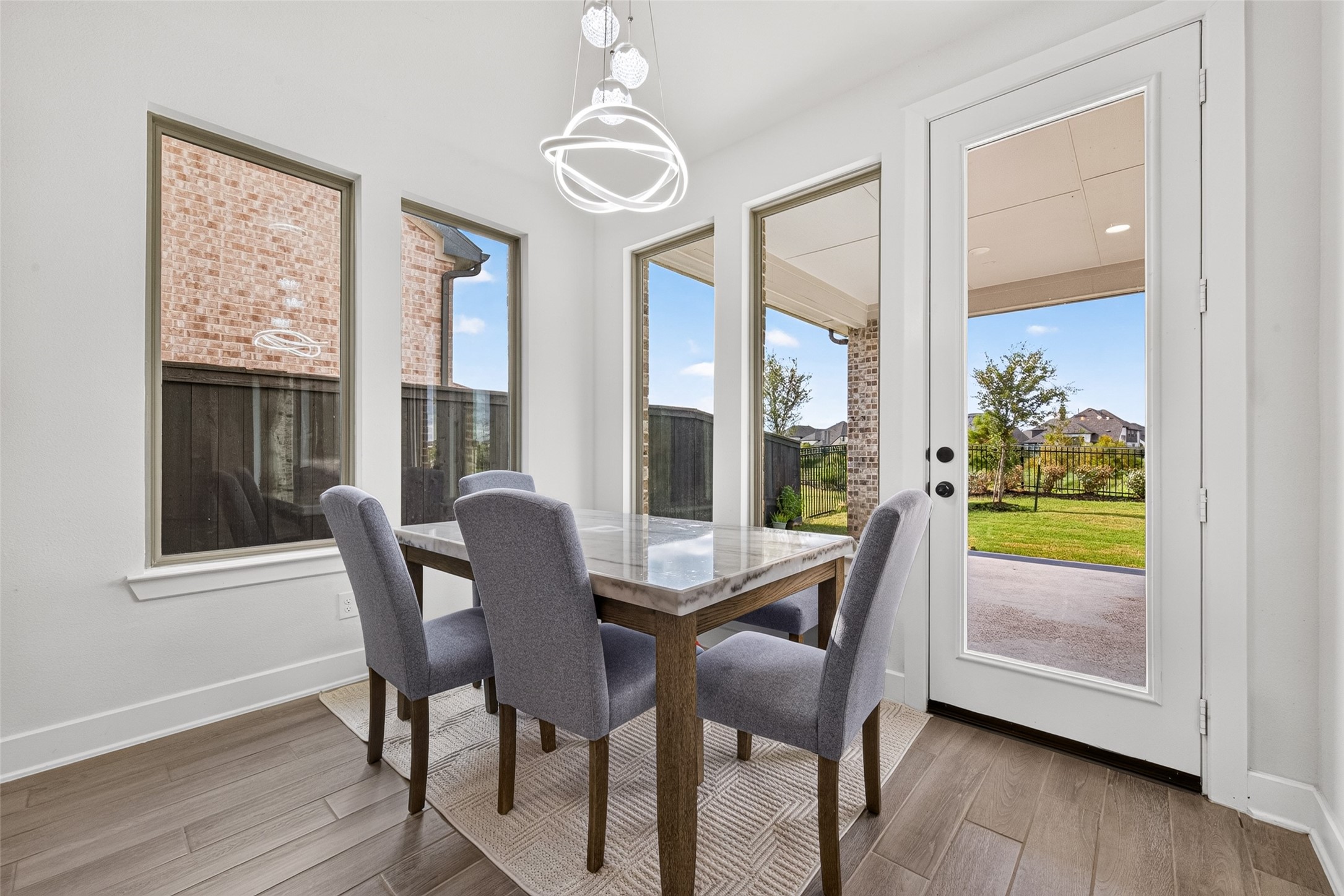 A sunlit breakfast area featuring expansive windows with serene views of the backyard and direct access to the patio, offering an elegant setting for casual dining and effortless indoor-outdoor living