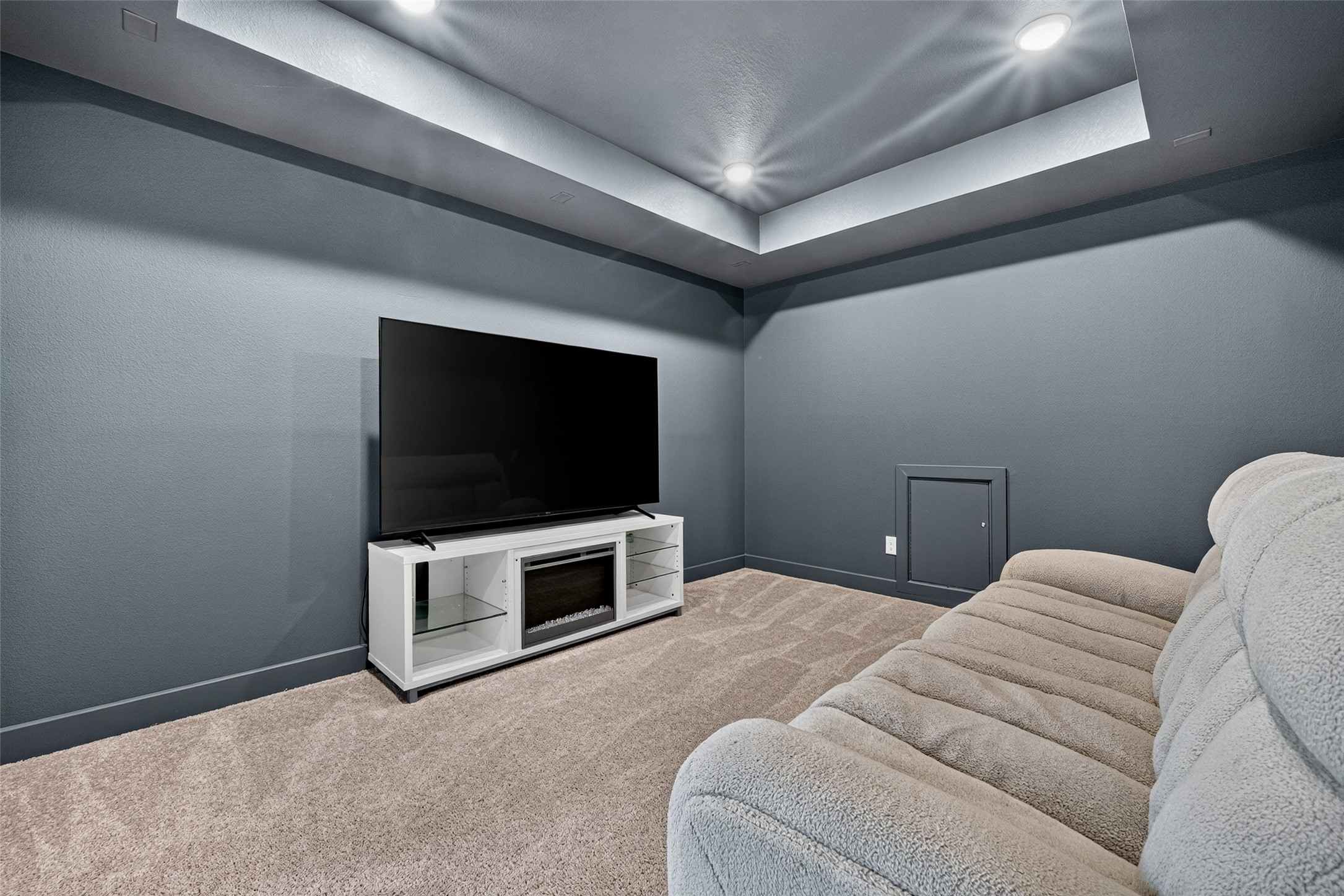 An expansive media room featuring elegant tray ceilings and refined recessed lighting, offering a sophisticated setting for immersive movie nights, premium entertainment, and unforgettable gatherings in the comfort of home.