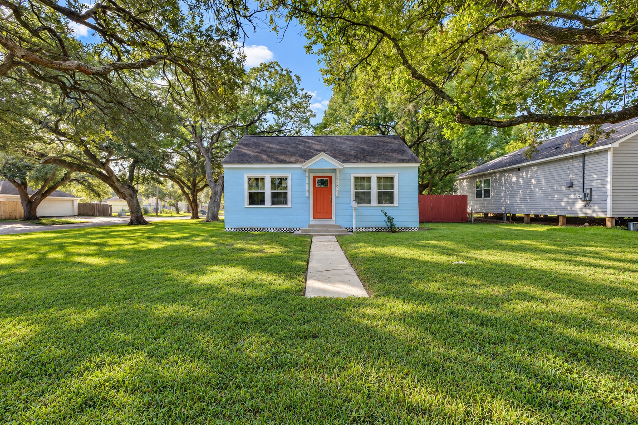 Curb appeal that makes you smile! The cheerful red front door, blue siding, and welcoming walkway give this house personality, while the generous front lawn adds valuable outdoor space.