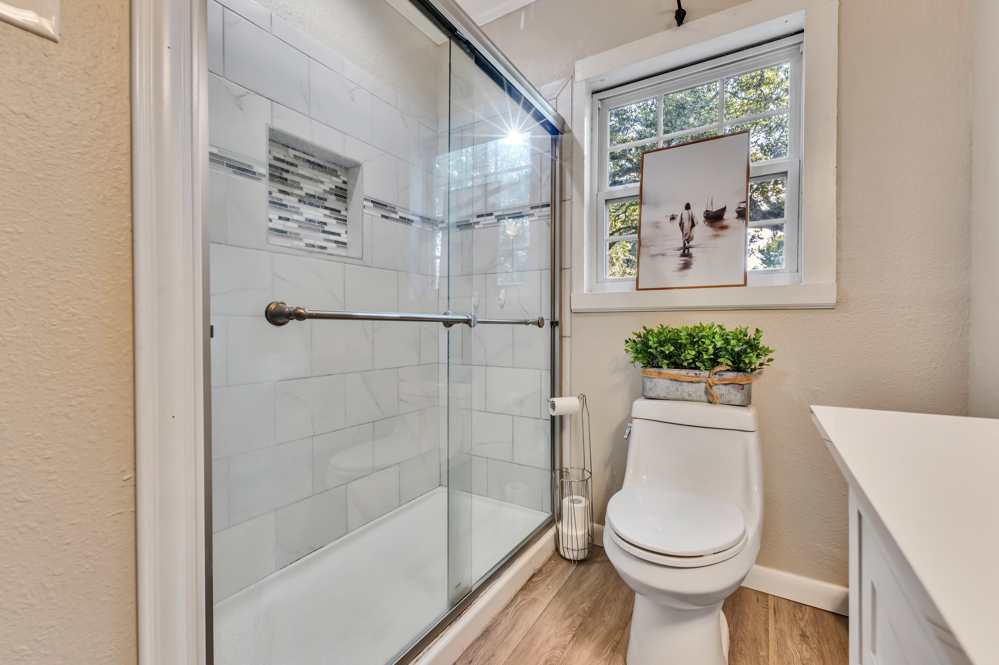 A glass-enclosed shower adds a clean, modern touch to this charming home. The tiled surround and natural light create an appealing space that balances style and everyday convenience.