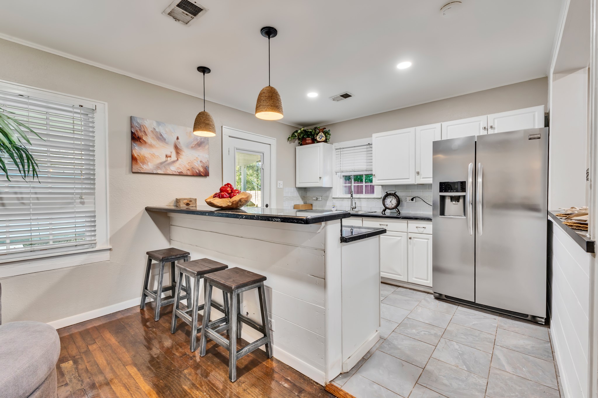 White cabinetry, stainless steel appliances, and dark countertops create a kitchen that feels fresh and functional. With practical counter space and a convenient breakfast bar, everyday meal preparation becomes a pleasure.