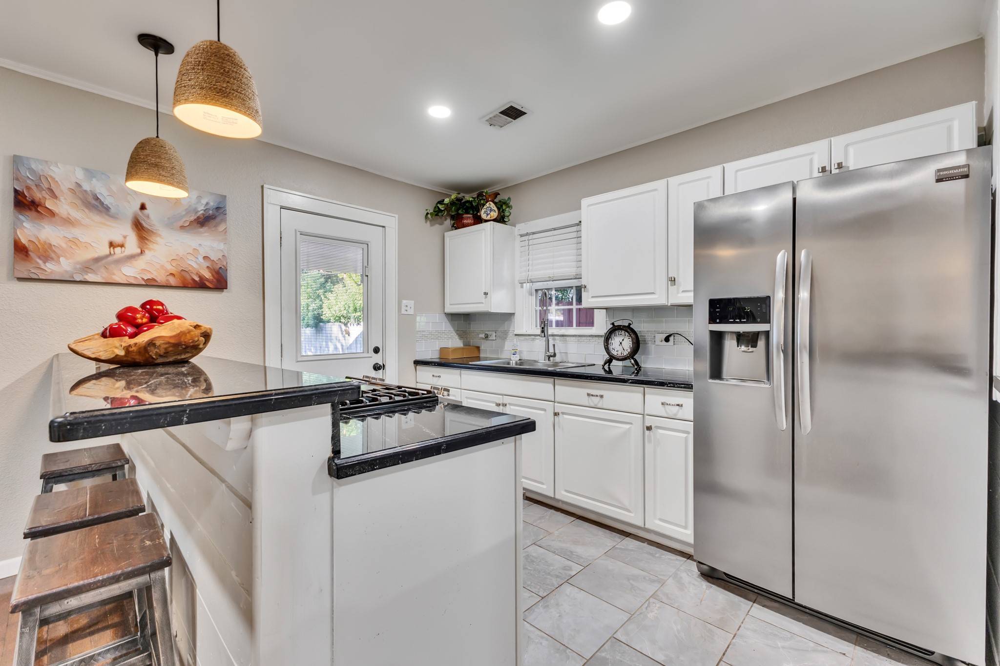 Style and practicality come together in this inviting kitchen. White cabinetry, stainless steel appliances, and durable-looking tiled flooring create an attractive space designed for everyday use.