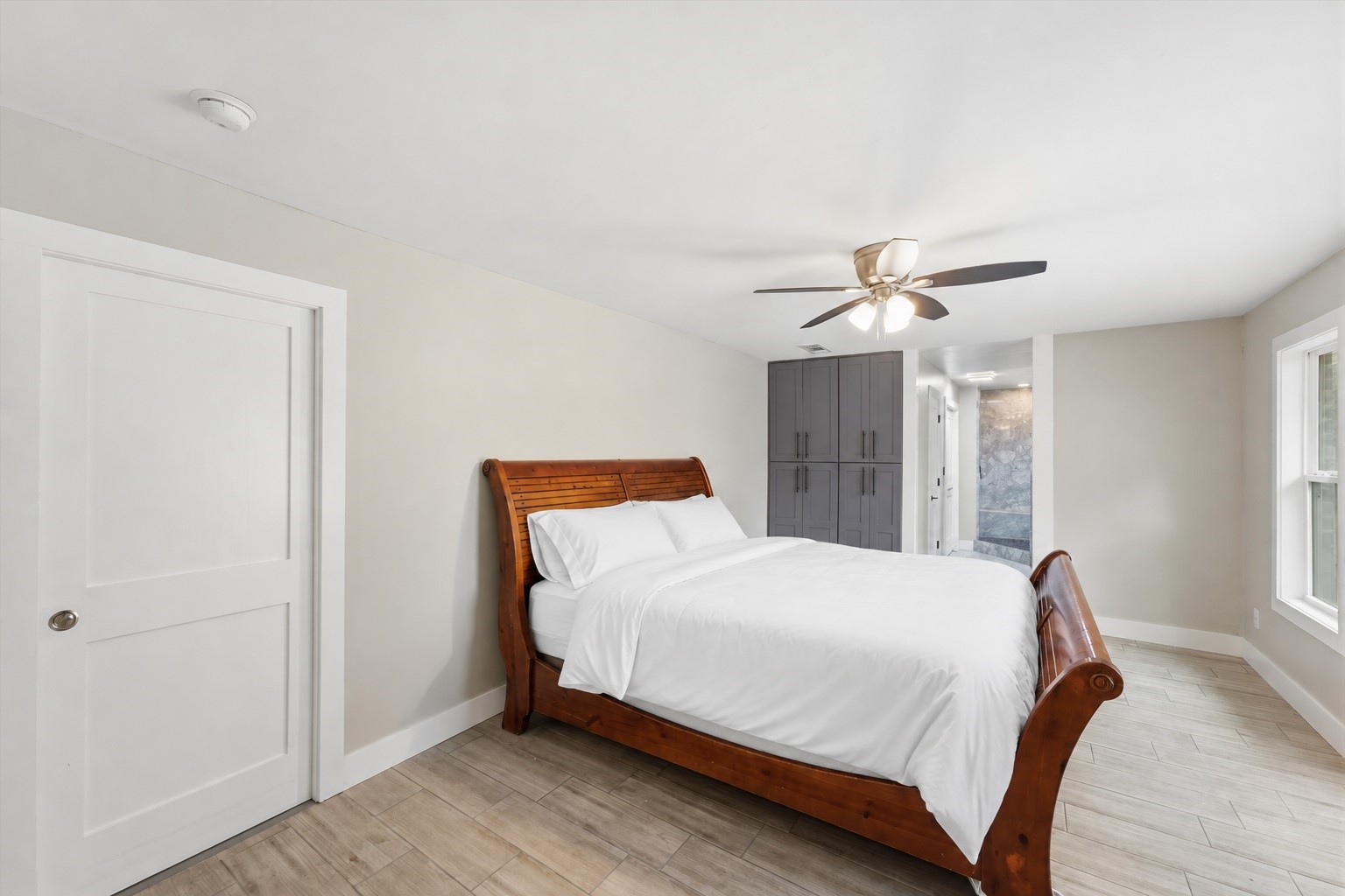 Additional view of the second primary suite, showing the room's layout and wood-like tile flooring.