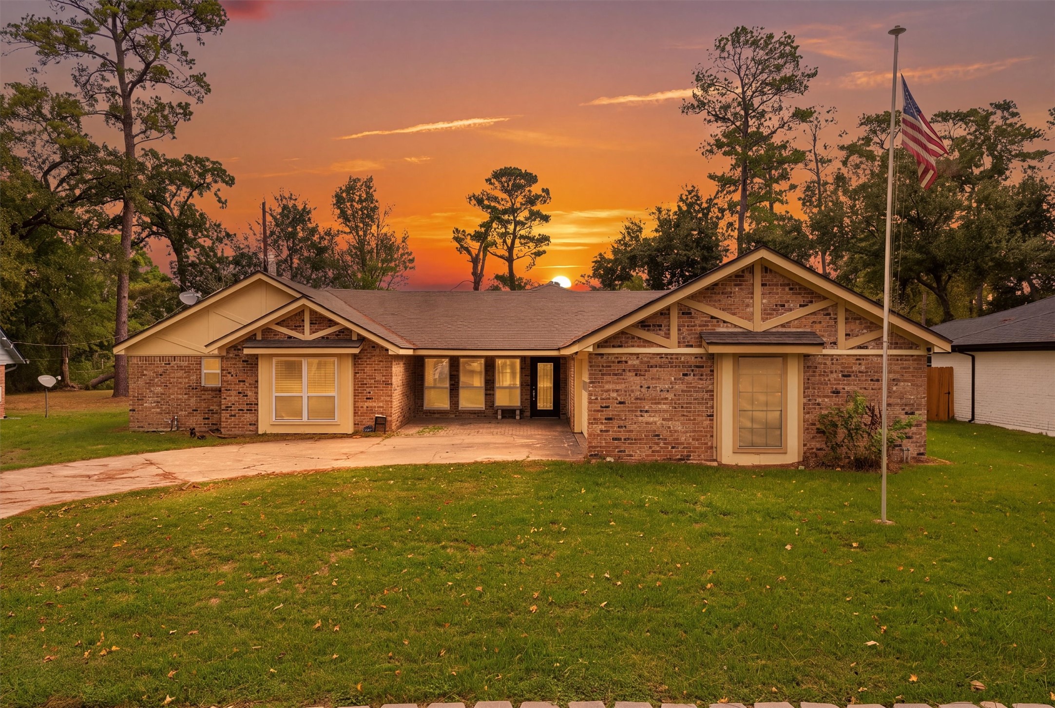 Single-story ranch-style brick home surrounded by mature trees, with a colorful Texas sunset in the background. Single-story ranch-style brick home surrounded by mature trees, with a colorful Texas sunset in the background.