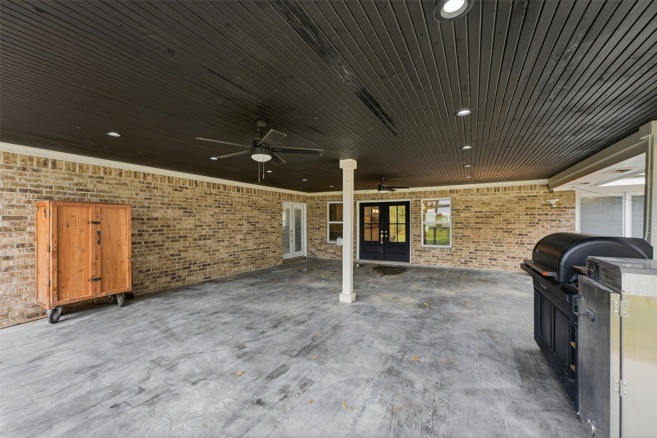 This expansive covered back patio, accessible from the living room and breakfast/dining area, offers a welcoming space for outdoor entertaining and relaxation. A dark wood-paneled ceiling, recessed lighting create a comfortable setting for gatherings year-round.