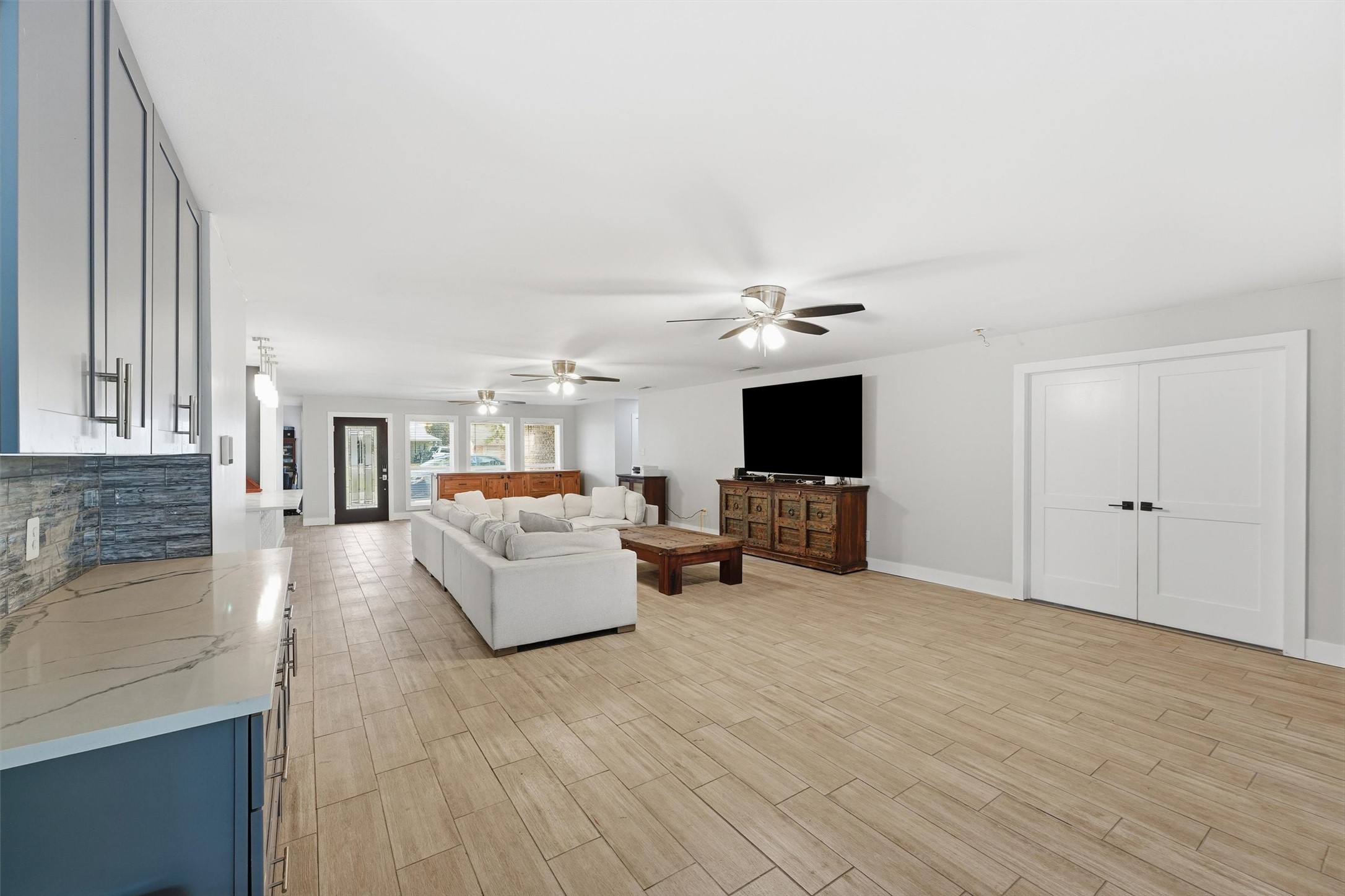 The large living area offers plenty of room for furniture and entertaining, with an adjoining butler's pantry featuring dark cabinetry, quartzite countertops, and tile backsplash.
