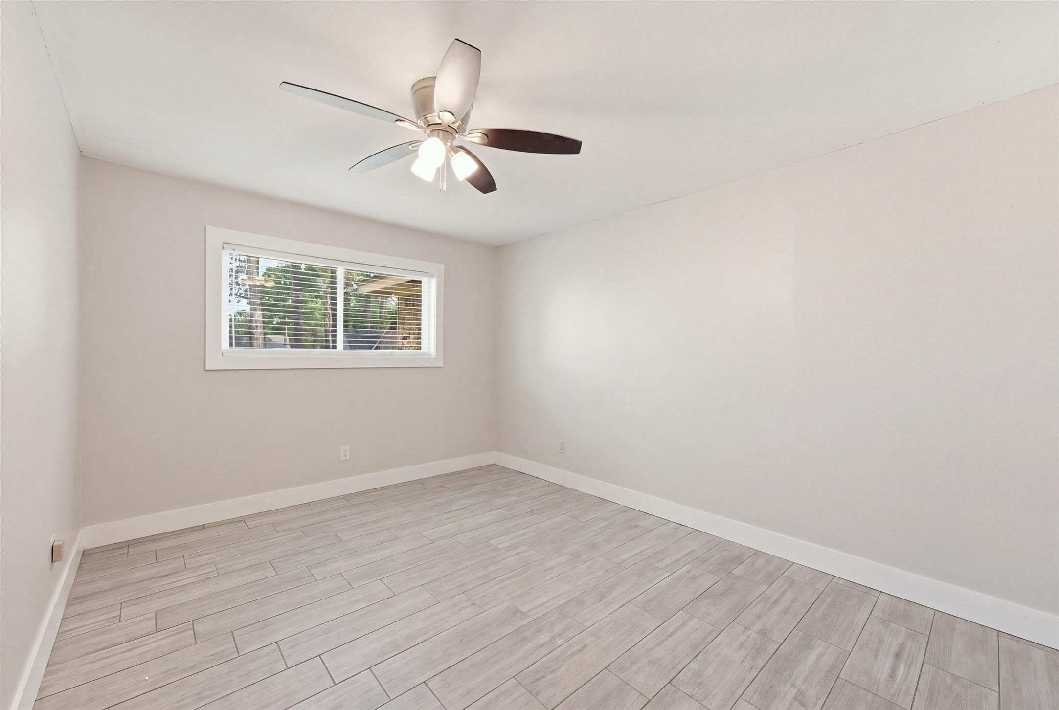 The third bedroom features wood-like tile flooring, neutral wall colors, and a functional layout that offers flexibility for guests or everyday use.