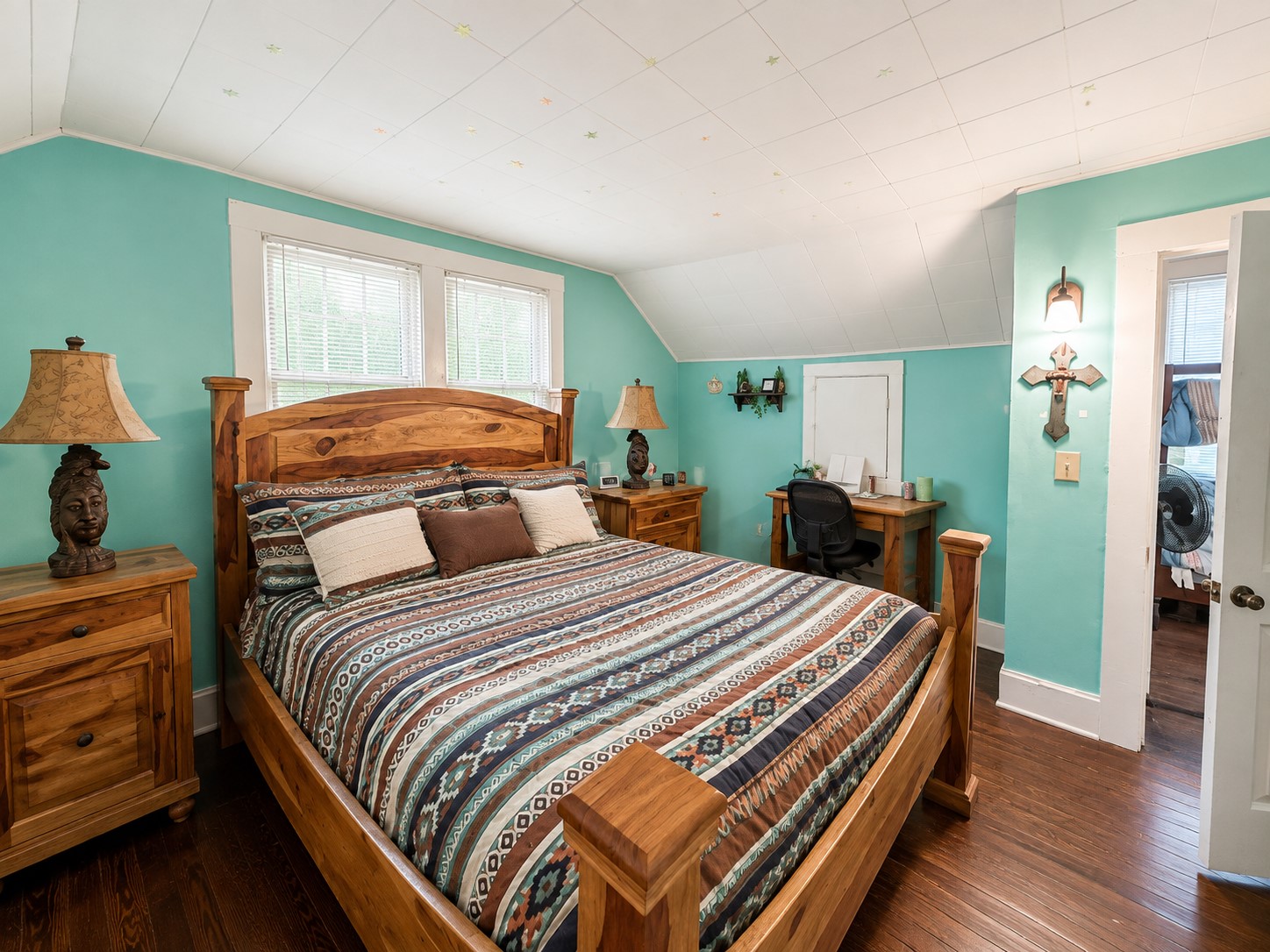 This view highlights the rooms generous proportions, natural light from multiple windows, and additional space suitable for a desk or sitting area.