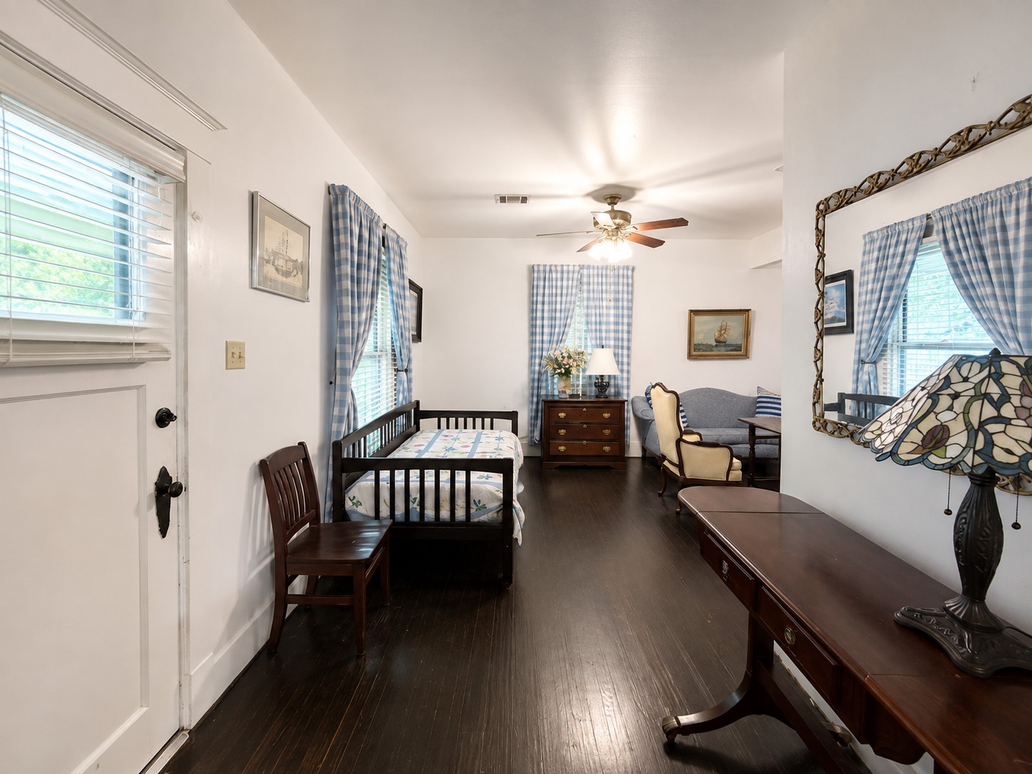 Spacious living area with dark wood flooring, built-in shelving and cabinetry, and an open connection to the adjacent dining space. Crisp white walls and trim create a bright contrast with the rich flooring.
